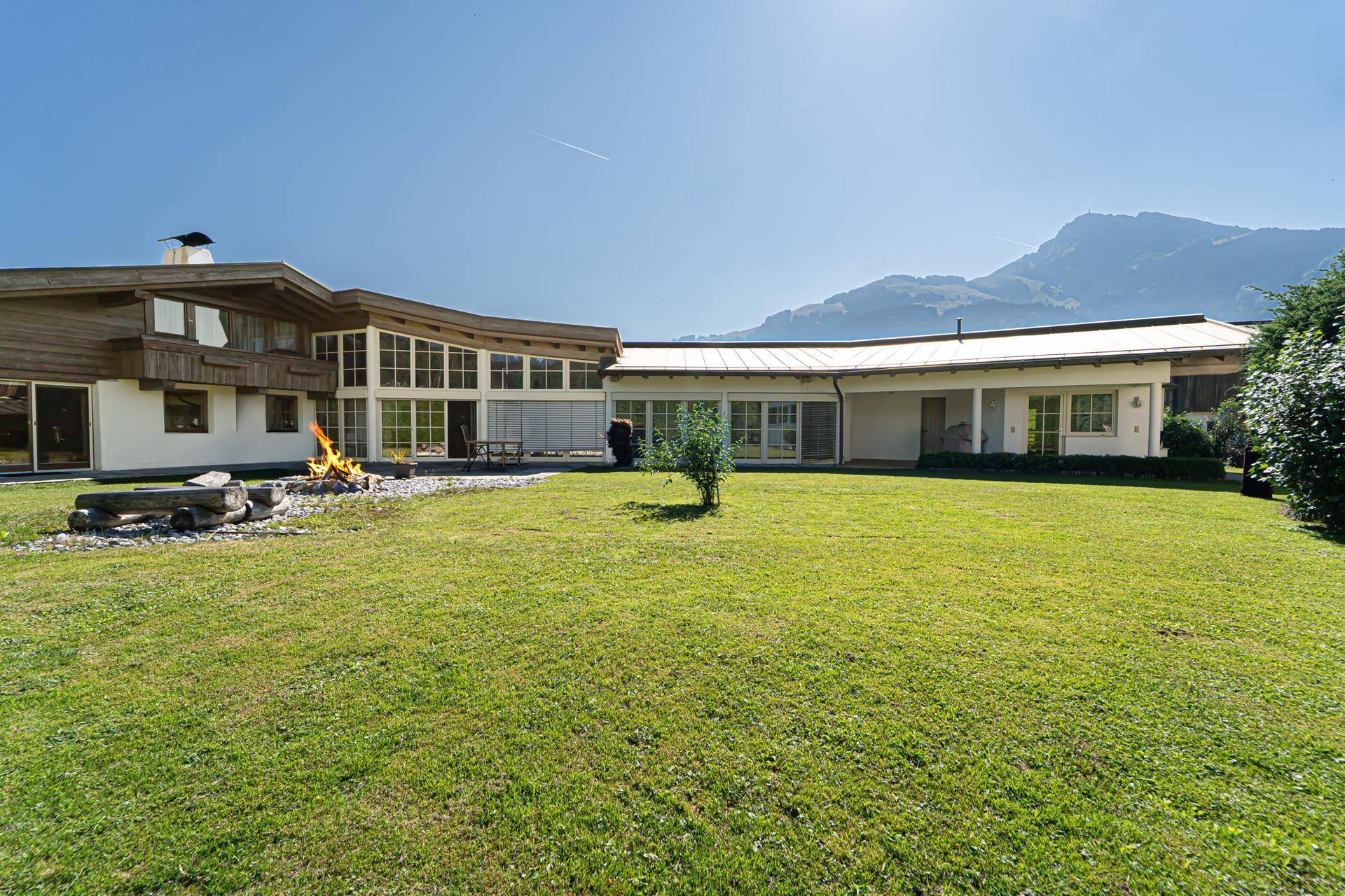 Weitläufiger Gartenbereich mit gepflegtem Rasen und Blick auf die umliegende Berglandschaft.