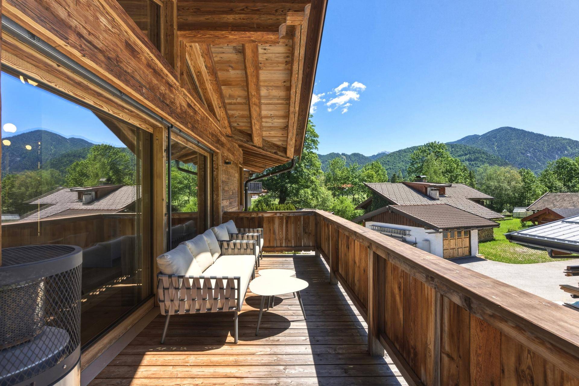 Sonniger Holzbalkon mit bequemen Outdoor-Möbeln und herrlichem Bergblick auf die Berge.