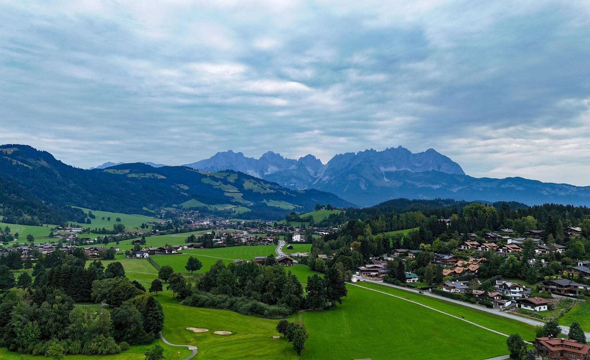 Panoramablick auf eine malerische Berglandschaft mit grünen Hügeln und einem charmanten Dorf.