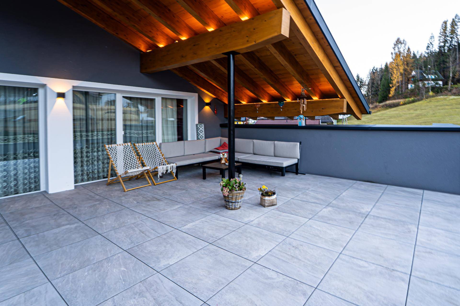 Große überdachte Terrasse mit bequemen Sitzgelegenheiten und Blick ins Grüne.