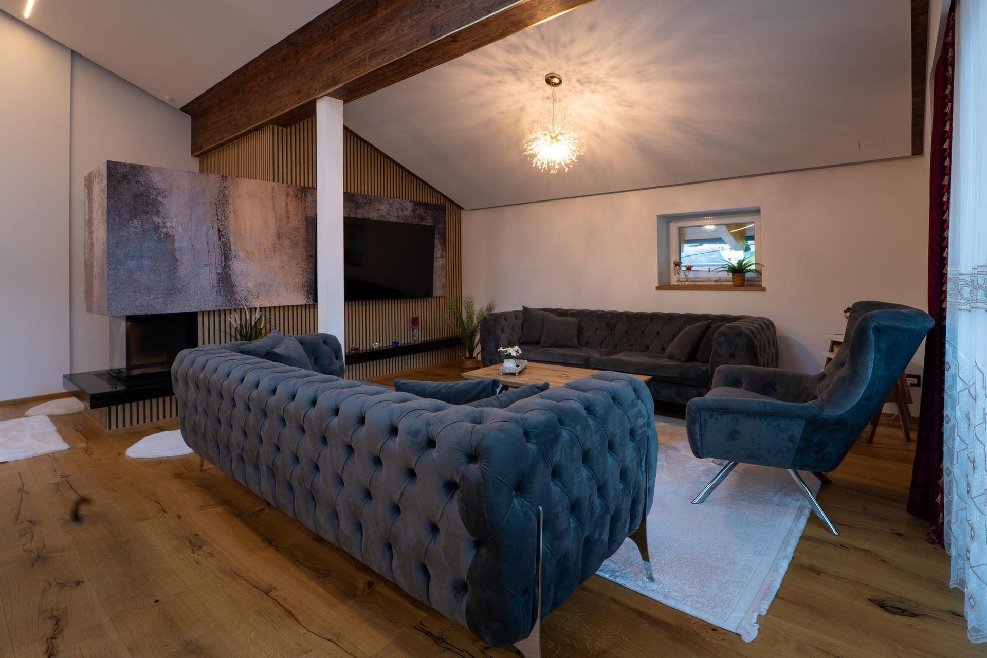 Gemütliches Wohnzimmer mit bequemen Sofas, Holzbalken und einem modernen Kaminbereich.