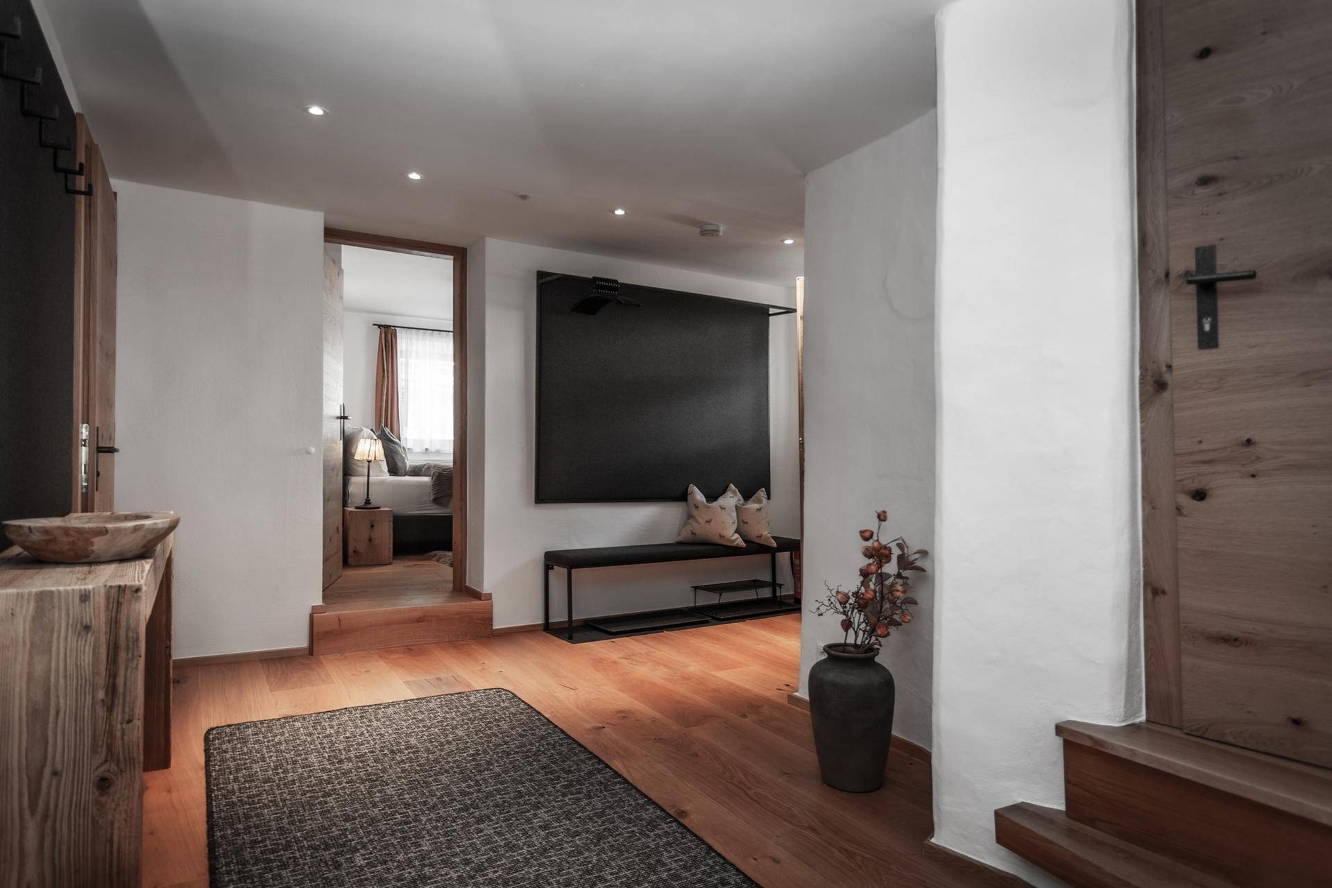 Heller Flur mit Holzboden, moderner Sitzbank und Zugang zu weiteren Räumen.