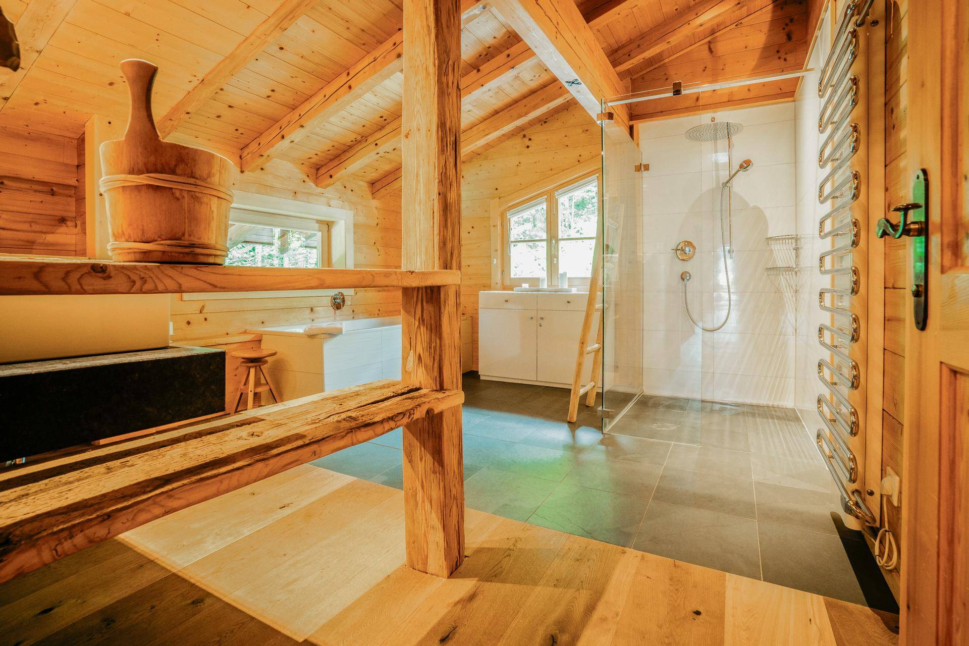 Modernes Badezimmer mit begehbarer Dusche, Badewanne und Holzelementen unter einer Dachschräge.