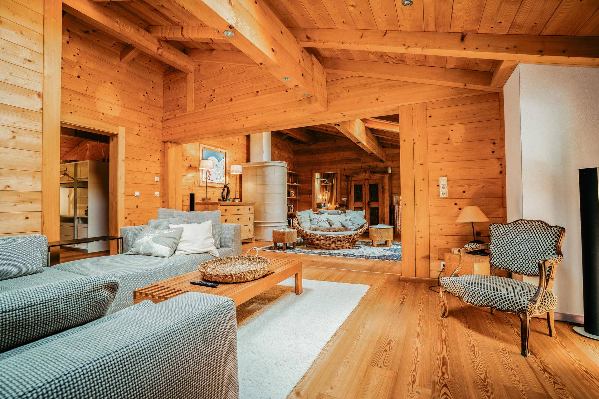 Gemütlicher Wohnbereich mit Holzböden und -wänden, Kaminofen und bequemen Sofas im alpinen Stil.
