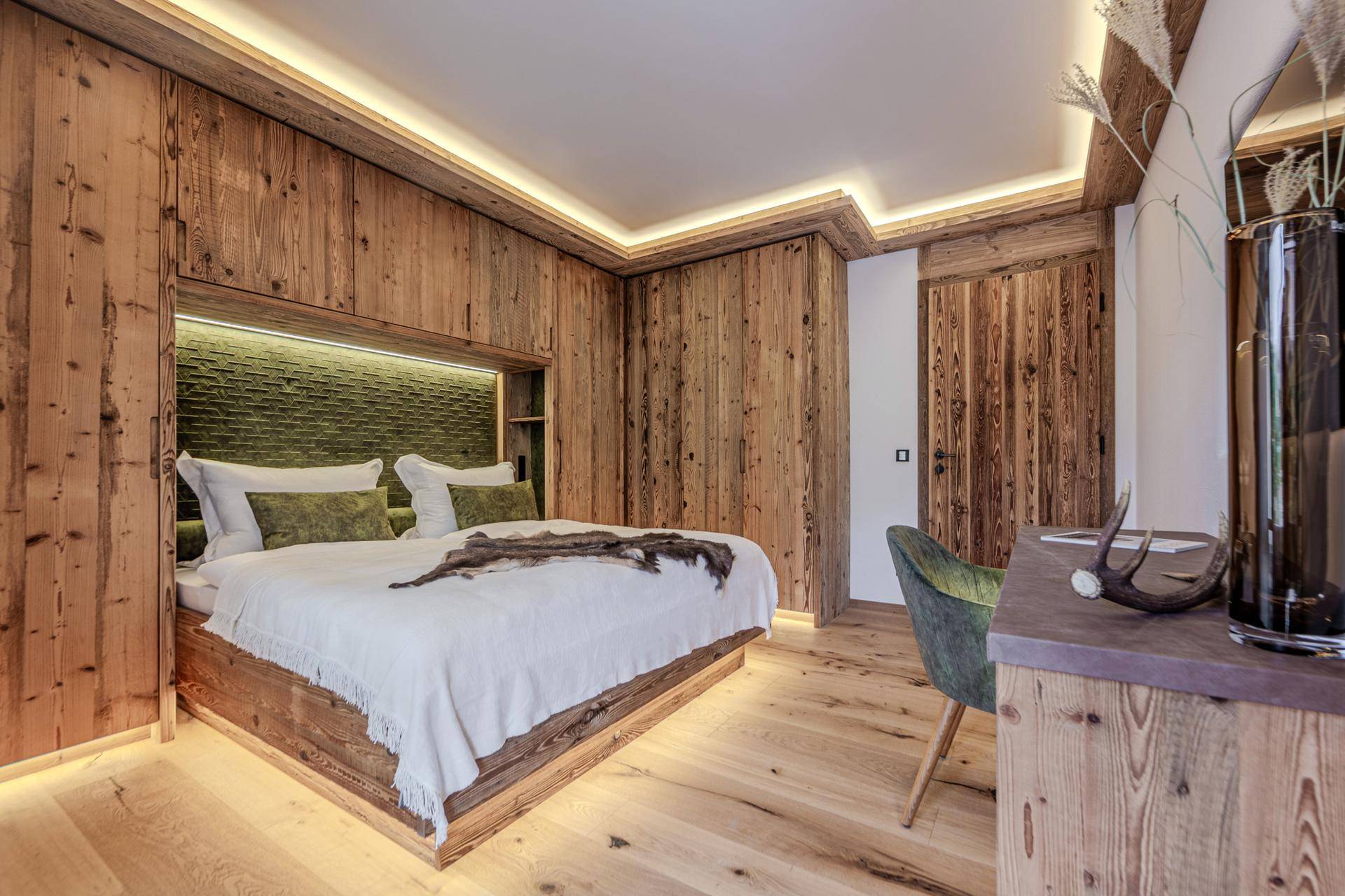 Modernes Schlafzimmer mit Holzwänden, integrierten Schränken und indirekter Beleuchtung.