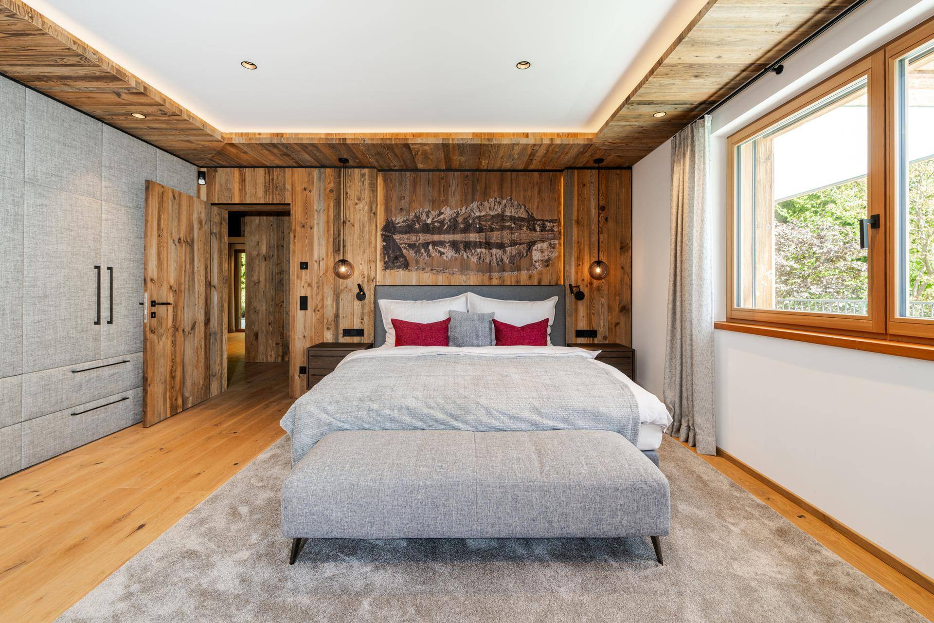 Gemütliches Schlafzimmer mit Holzwand, integriertem Kleiderschrank und großem Fenster für viel Licht.