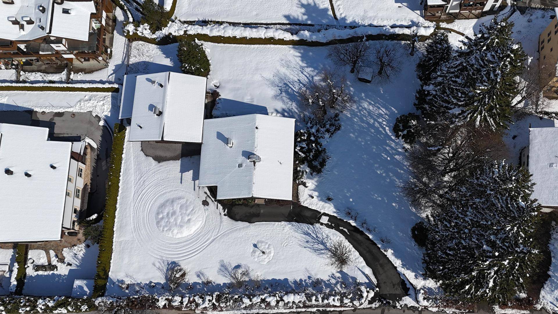 Luftaufnahme des Anwesens im Winter, zeigt zwei schneebedeckte Häuser, Zufahrt und umliegende verschneite Landschaft.