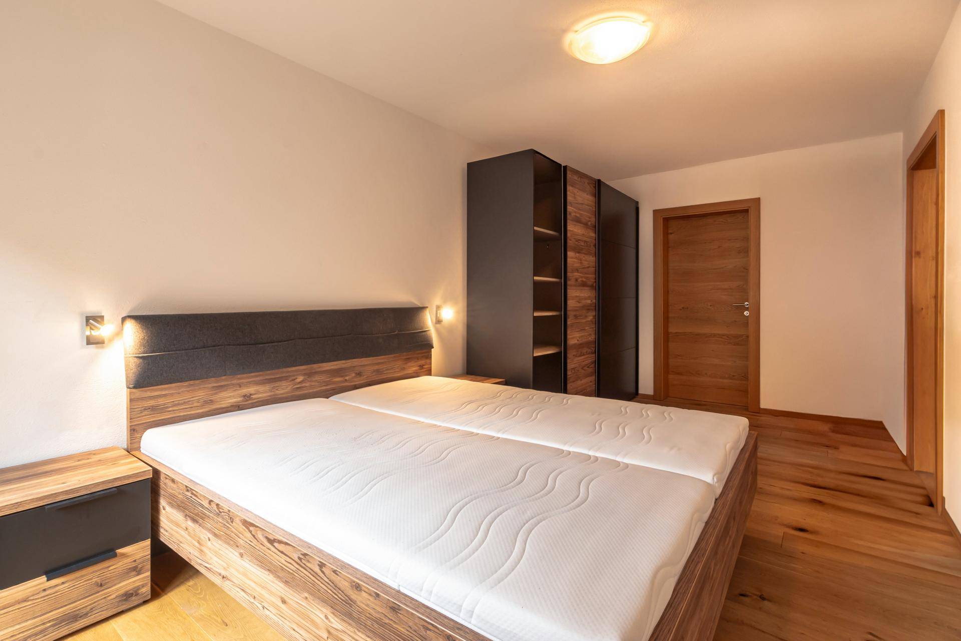 Komfortables Schlafzimmer mit Doppelbett, Holzmöbeln und integriertem Kleiderschrank.