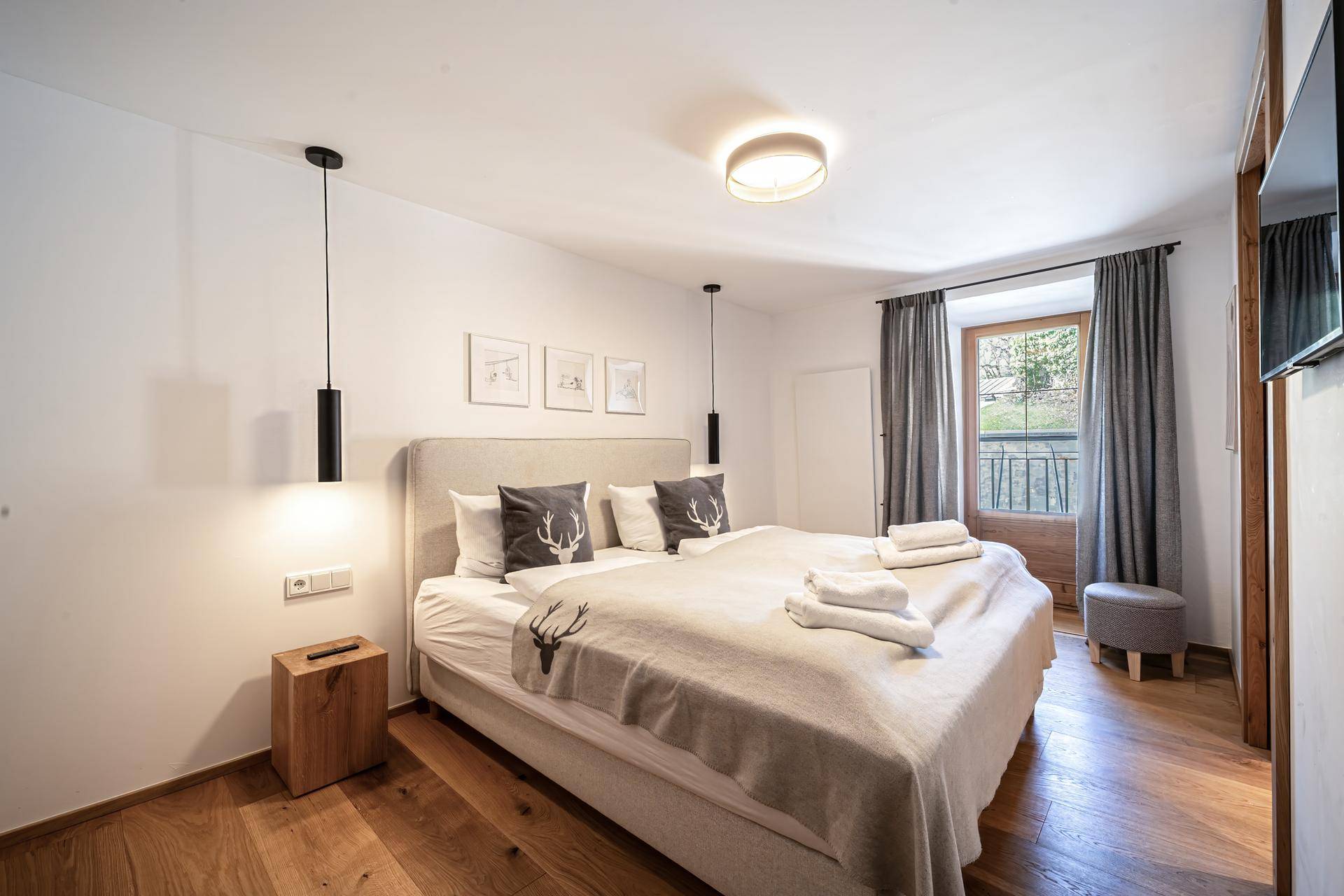 Modernes Schlafzimmer mit Doppelbett, Holzboden und Zugang zu einem französischen Balkon.