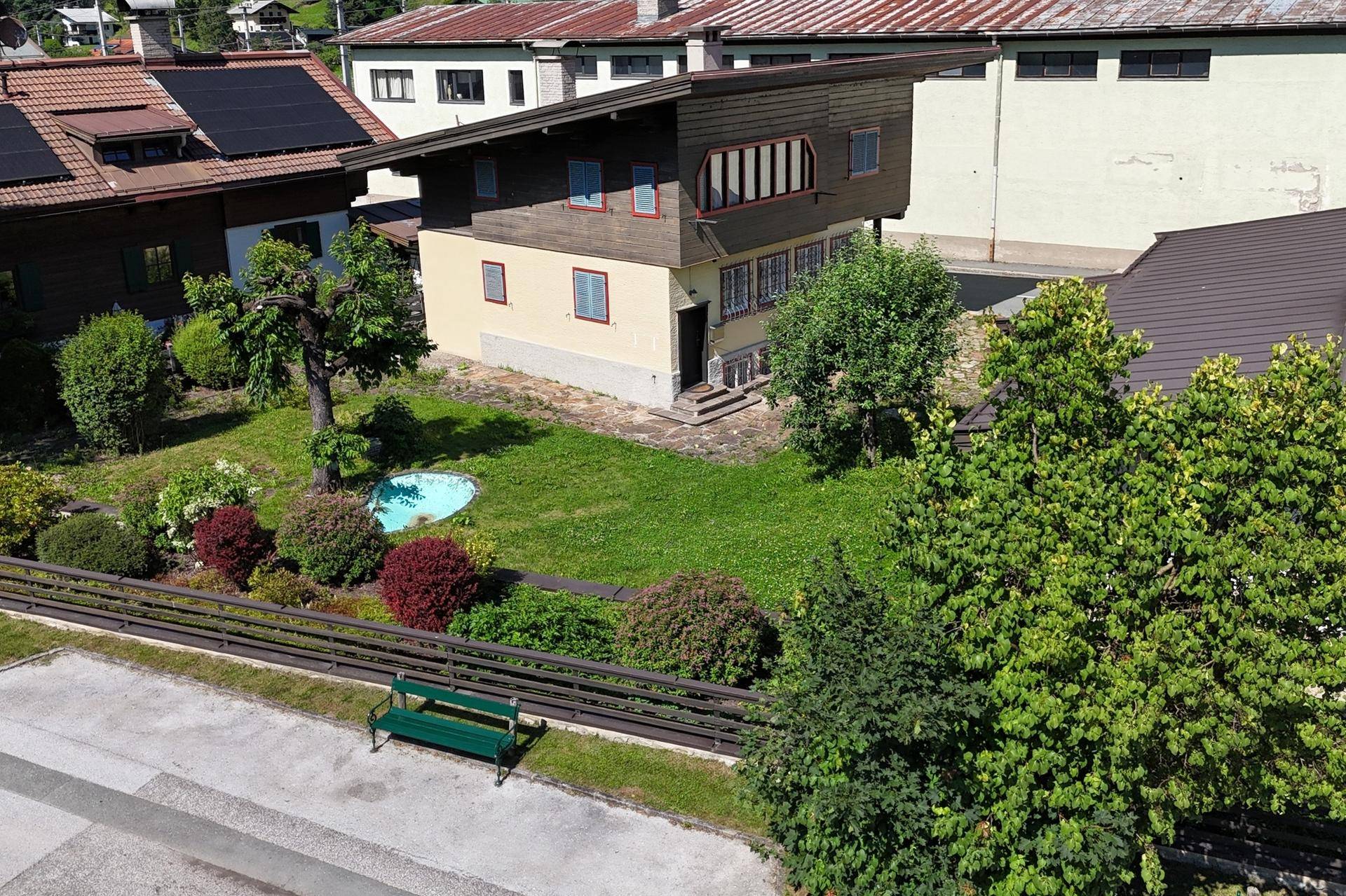 Gepflegter Gartenbereich mit Rasenfläche, Sträuchern und einem kleinen Teich vor dem Haus.