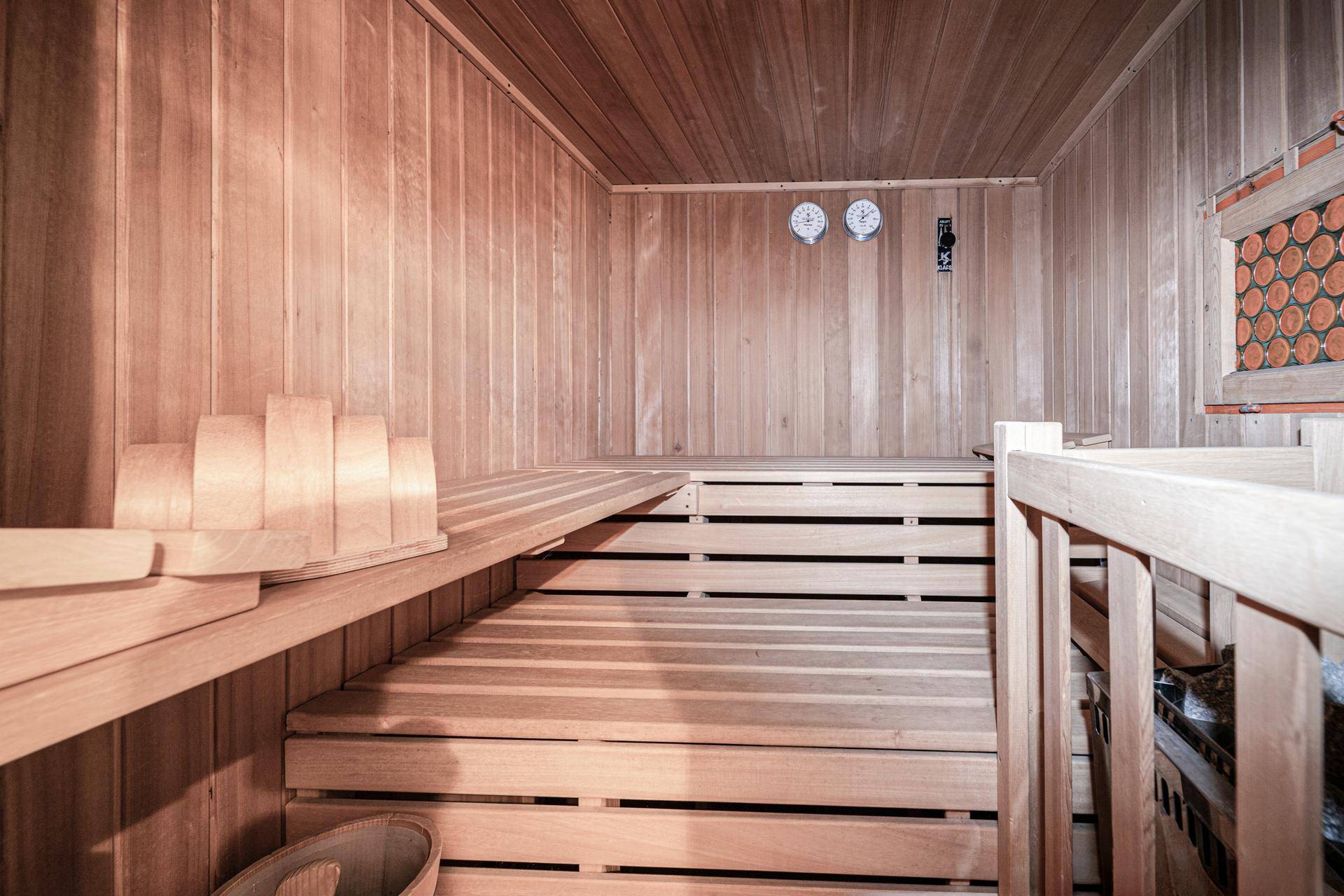 Geräumige Holzsauna mit mehreren Bänken und traditionellem Saunaofen.