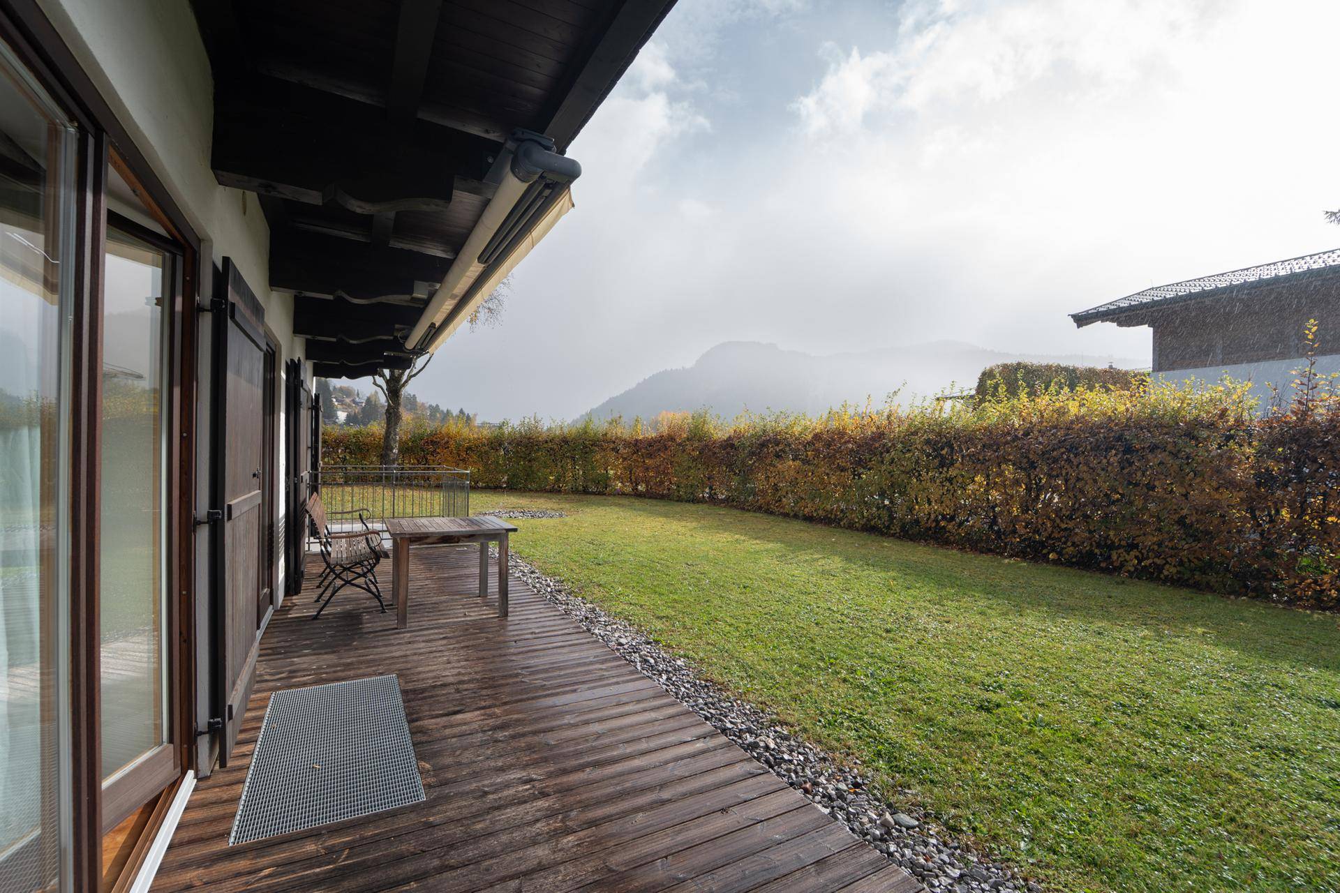 Große Holzterrasse mit Gartenmöbeln und Blick auf die umliegende Landschaft.