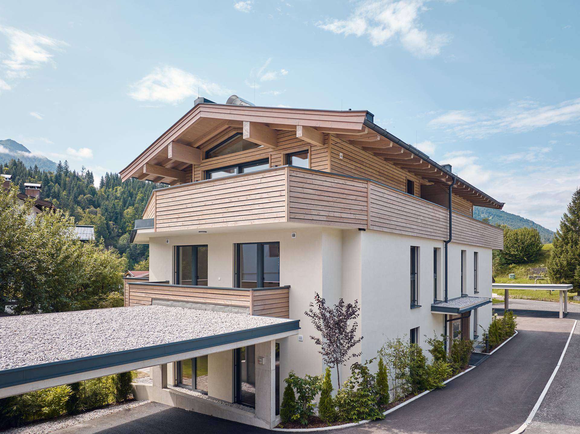 Attraktives Mehrfamilienhaus in alpiner Architektur mit Holzfassade und Carport.