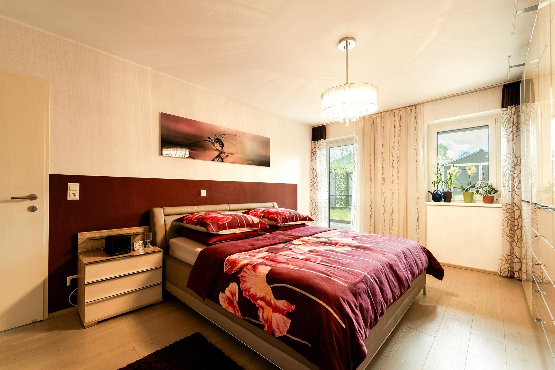 Gemütliches Schlafzimmer mit großem Bett, floraler Bettwäsche und Zugang zum Außenbereich.