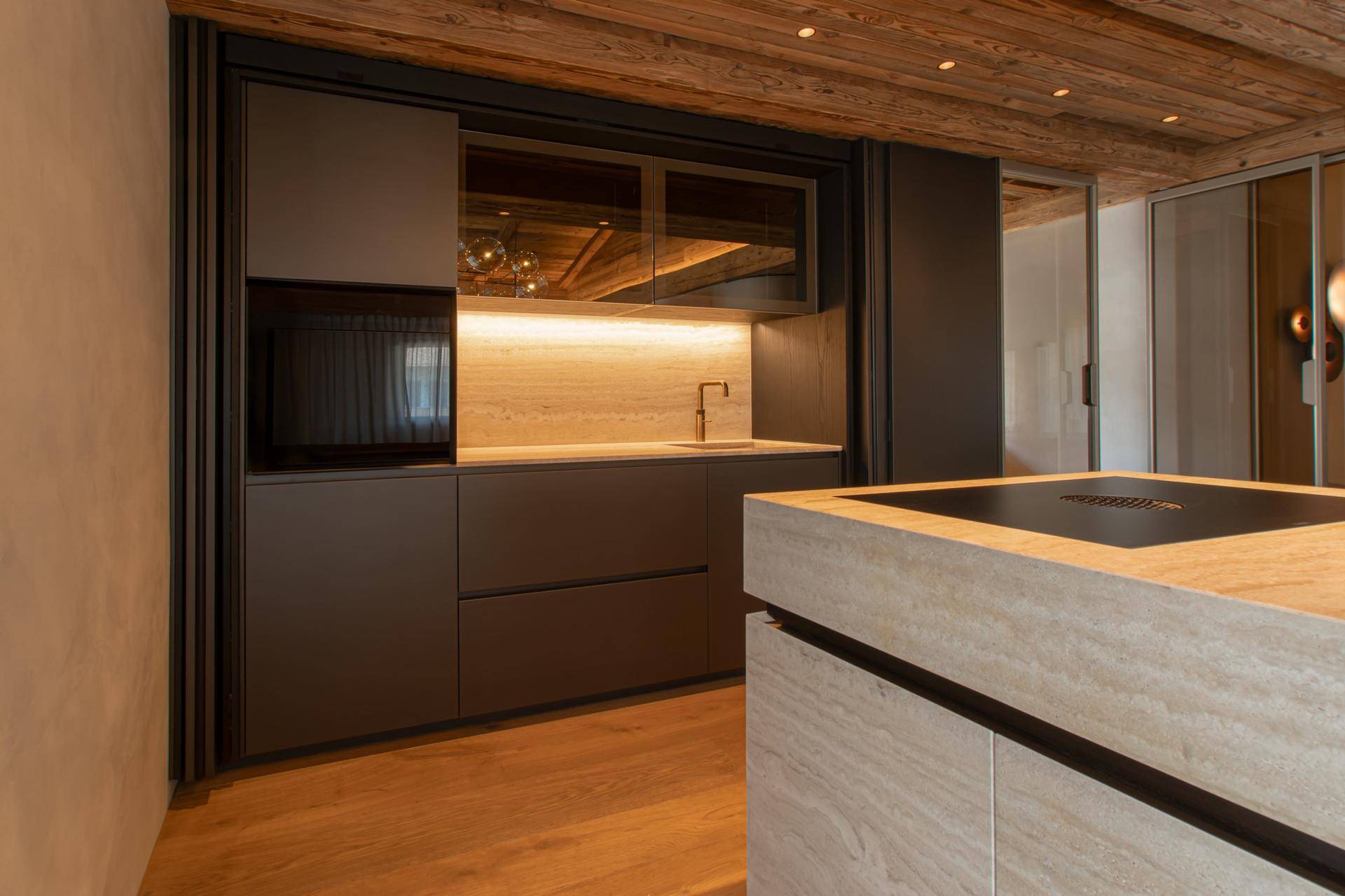 Elegante, moderne Küche mit dunklen Schränken, Stein-Arbeitsplatte und integrierten Geräten.