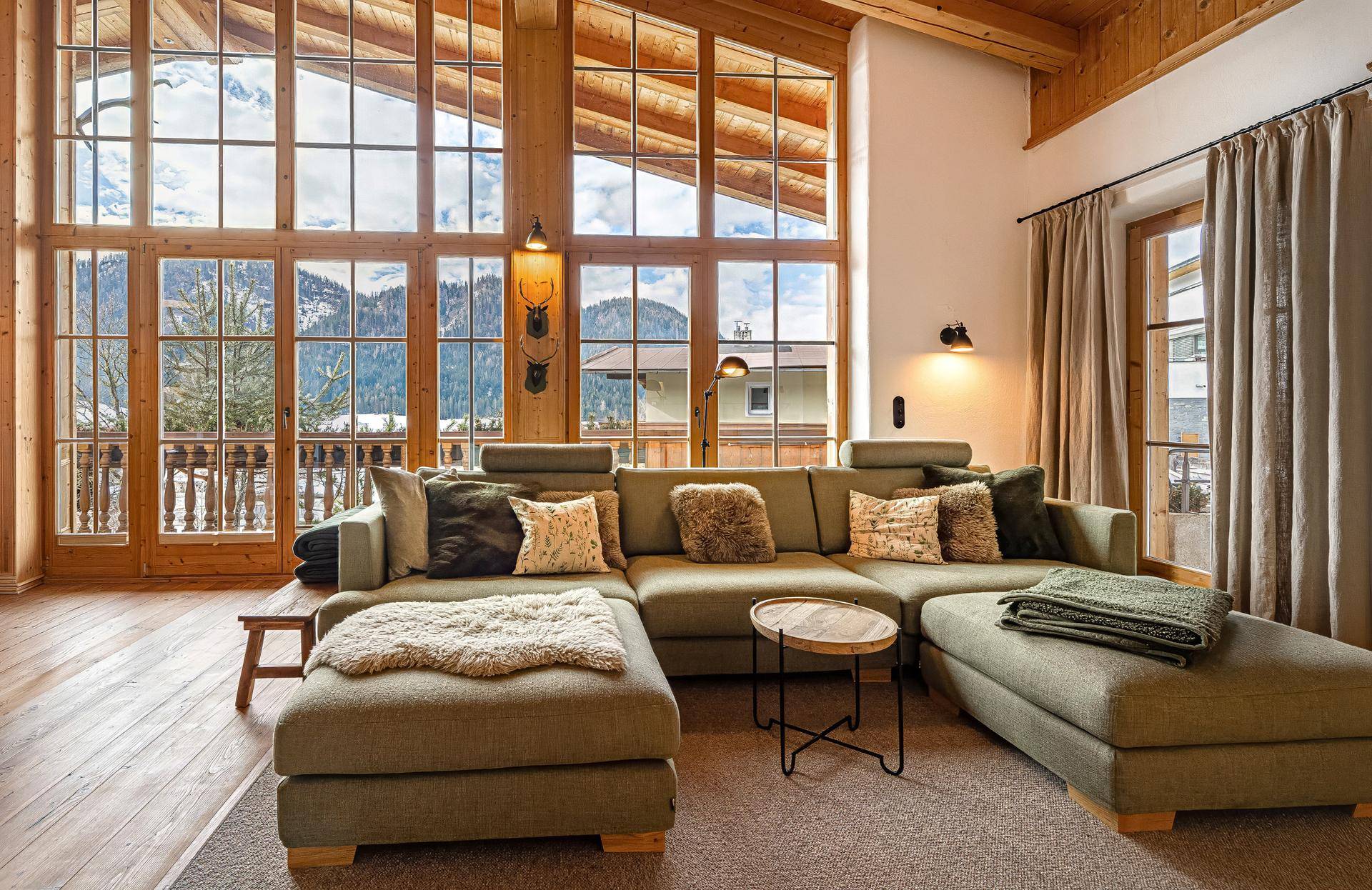 Großzügiges Wohnzimmer mit bequemer Couch, raumhohen Fenstern und beeindruckendem Bergblick.