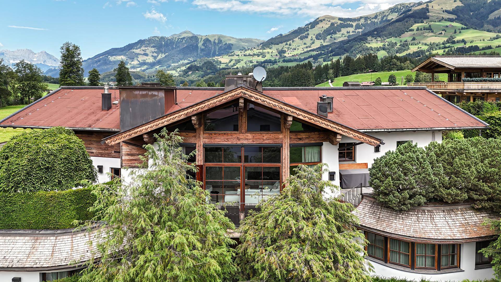 Großes Chalet mit Holzelementen und großen Fenstern in einer malerischen alpinen Berglandschaft.