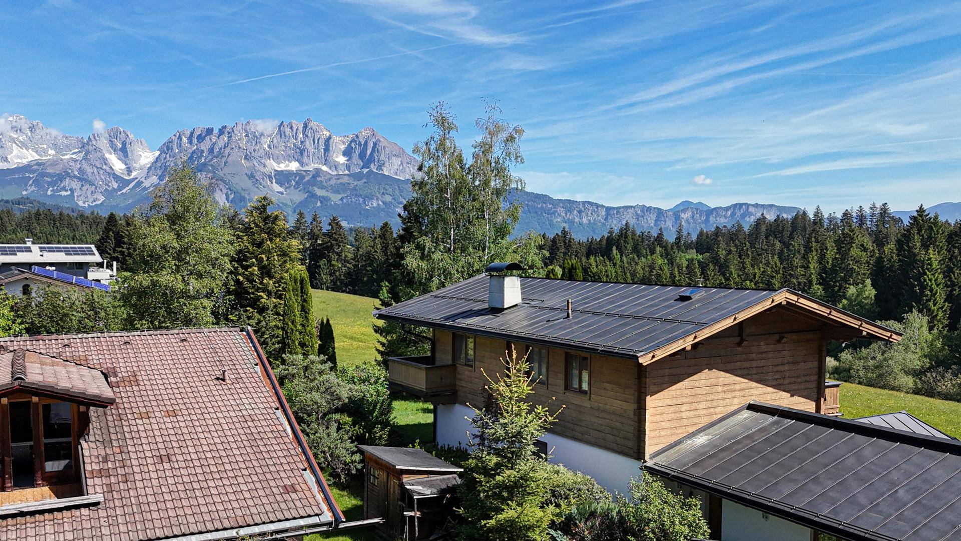 Luftaufnahme von Häusern in einer idyllischen Berglandschaft mit weitem Blick auf die Alpen.