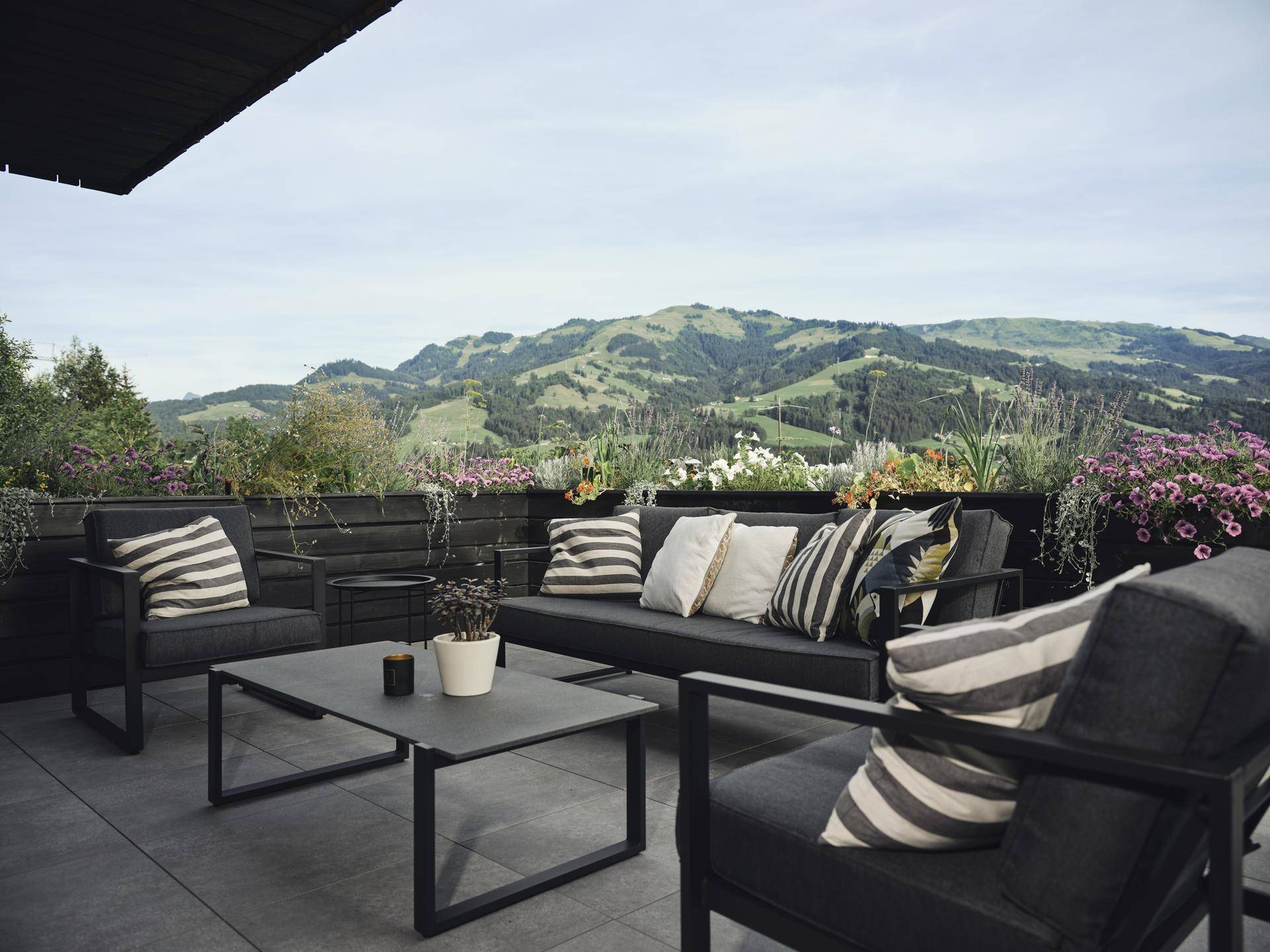 Gemütliche Lounge-Ecke auf dem Balkon mit bequemen Möbeln und atemberaubendem Blick auf die Berge.
