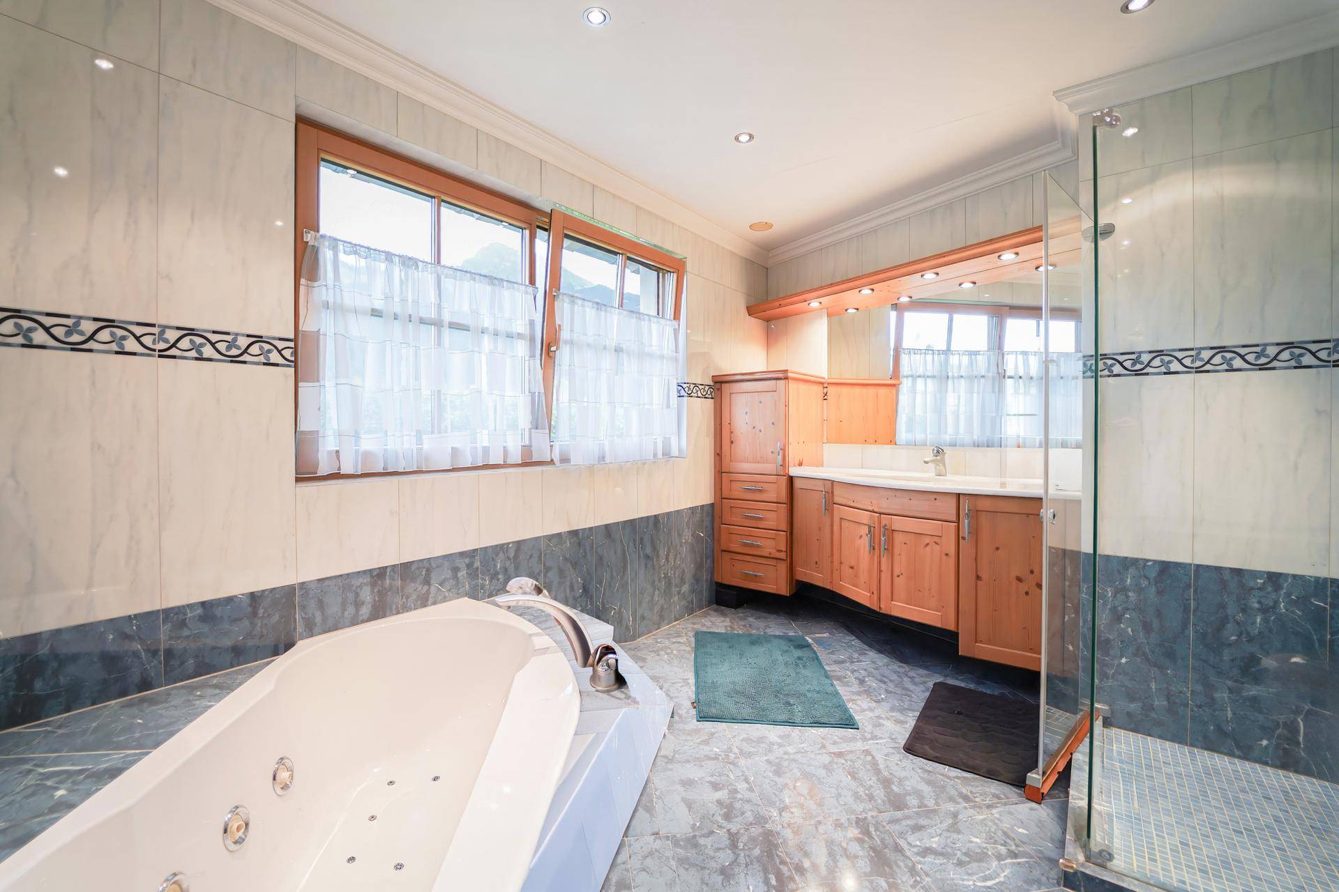 Geräumiges Badezimmer mit Whirlpool-Badewanne, Dusche und Holzwaschtisch.