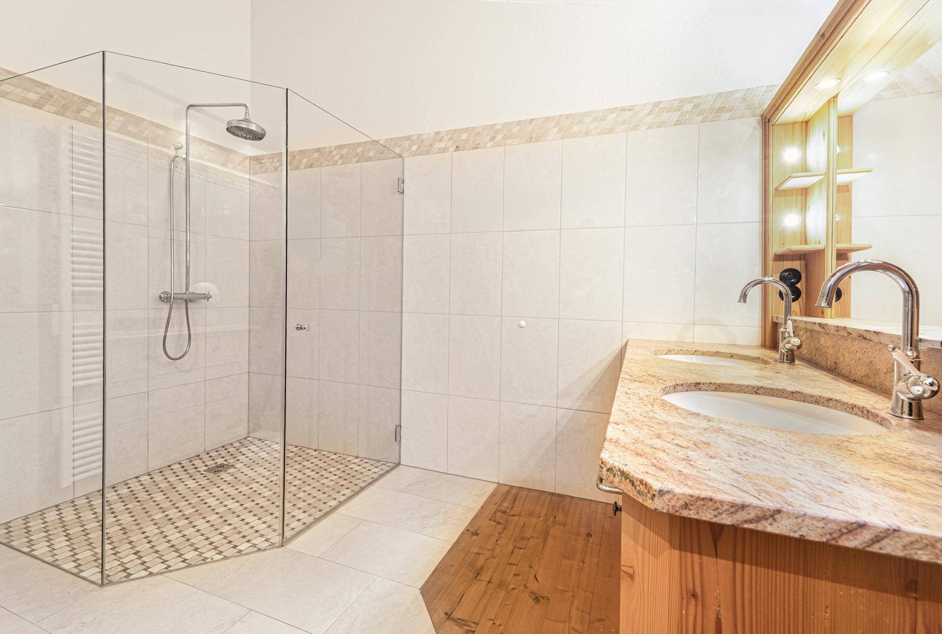 Modernes Badezimmer mit begehbarer Dusche, Doppelwaschbecken und hellen Fliesen.