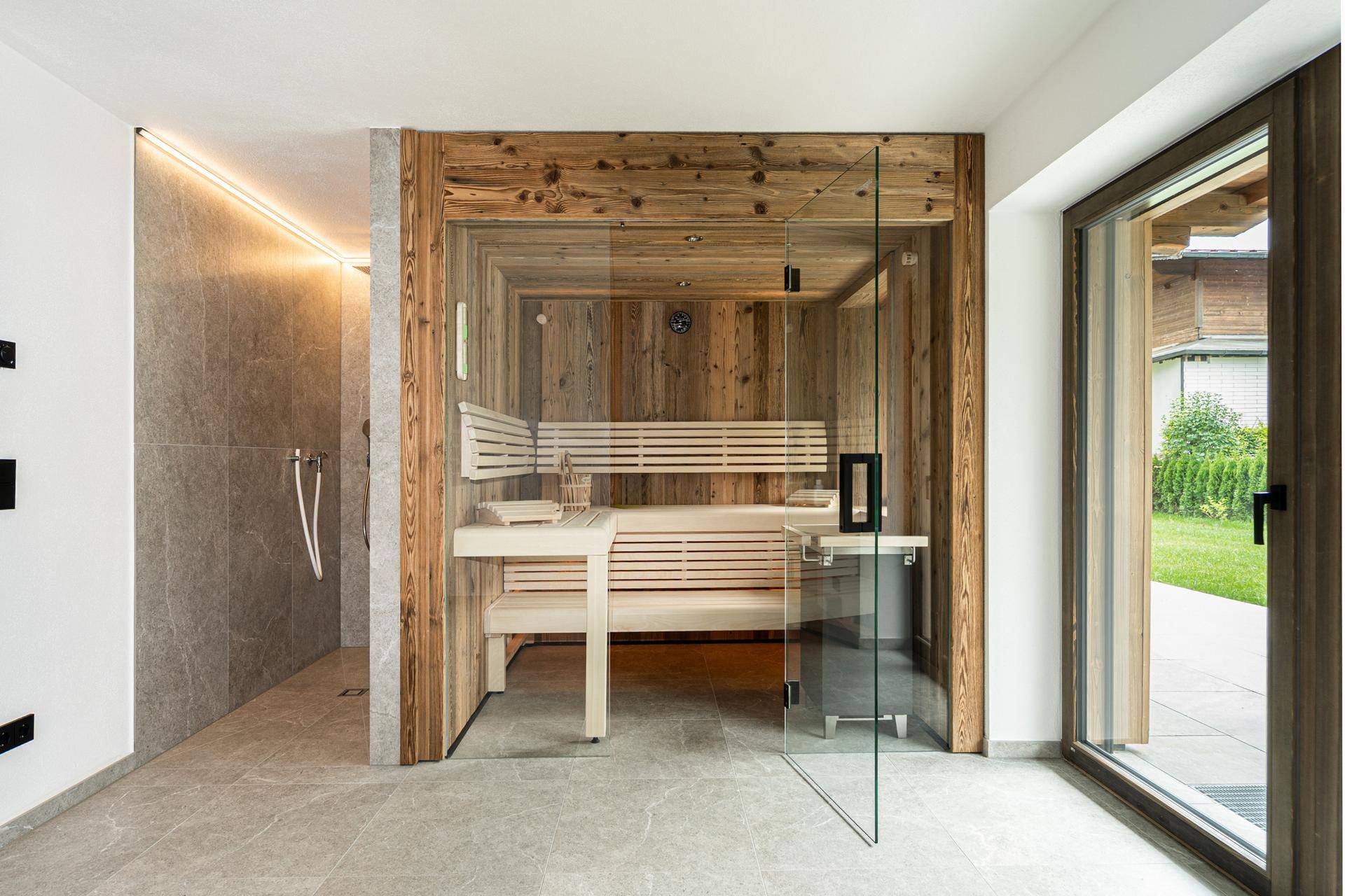 Exklusiver Wellnessbereich mit moderner Sauna, Dusche und Zugang zum Garten.