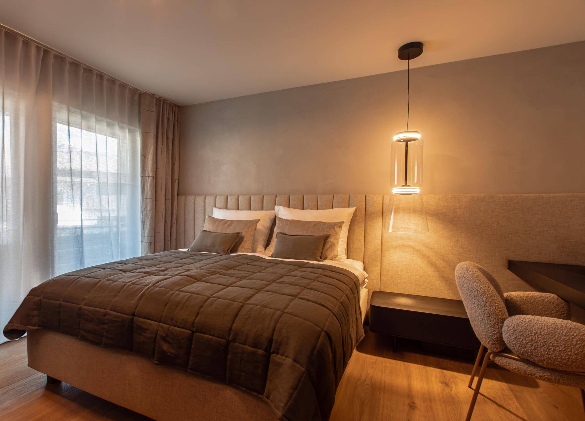 Gemütliches Schlafzimmer mit großem Bett, Holzboden und Vorhängen für Privatsphäre.