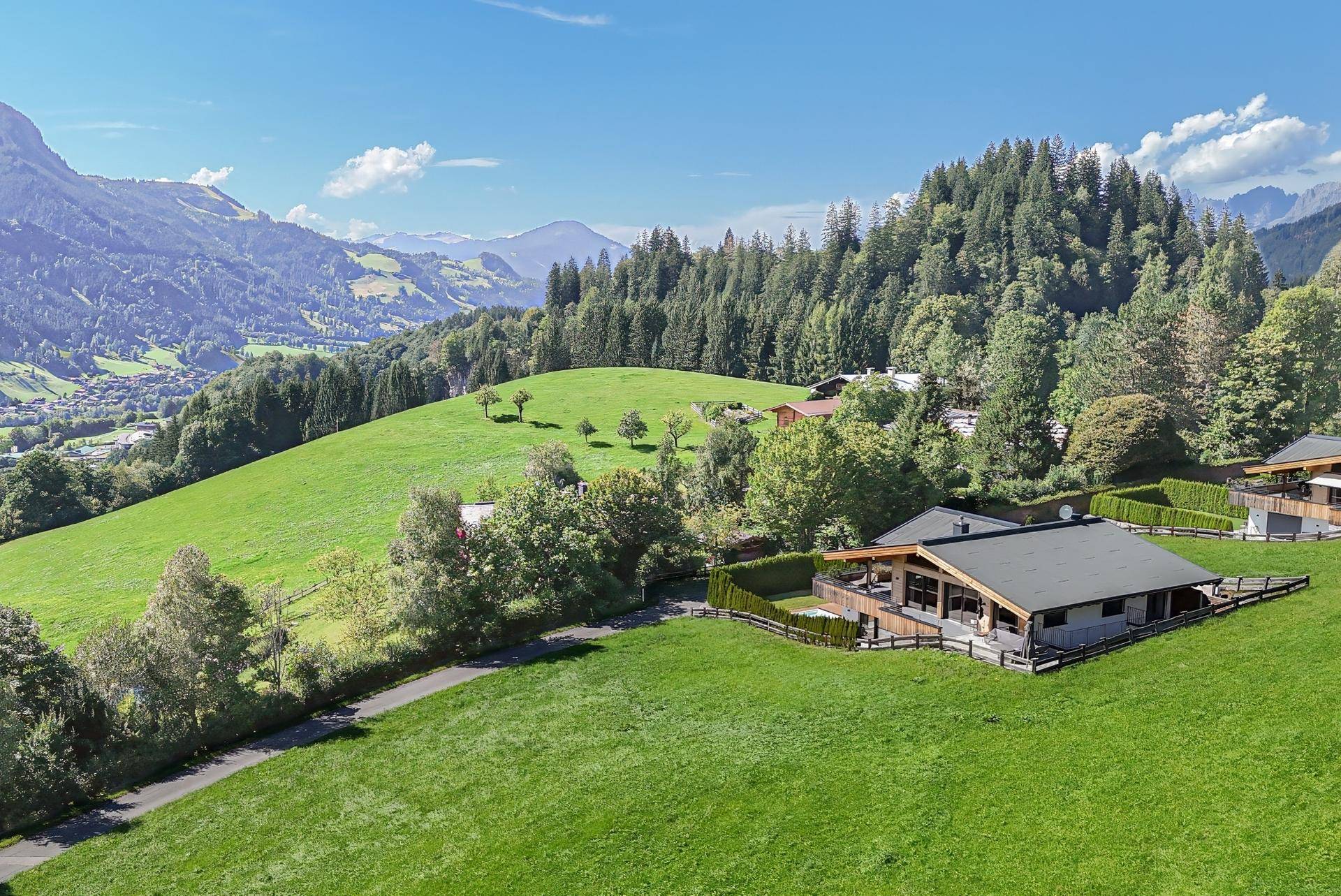 Weitläufige Ansicht des Chalets in einer idyllischen Bergregion mit weiten grünen Hängen und Wäldern.