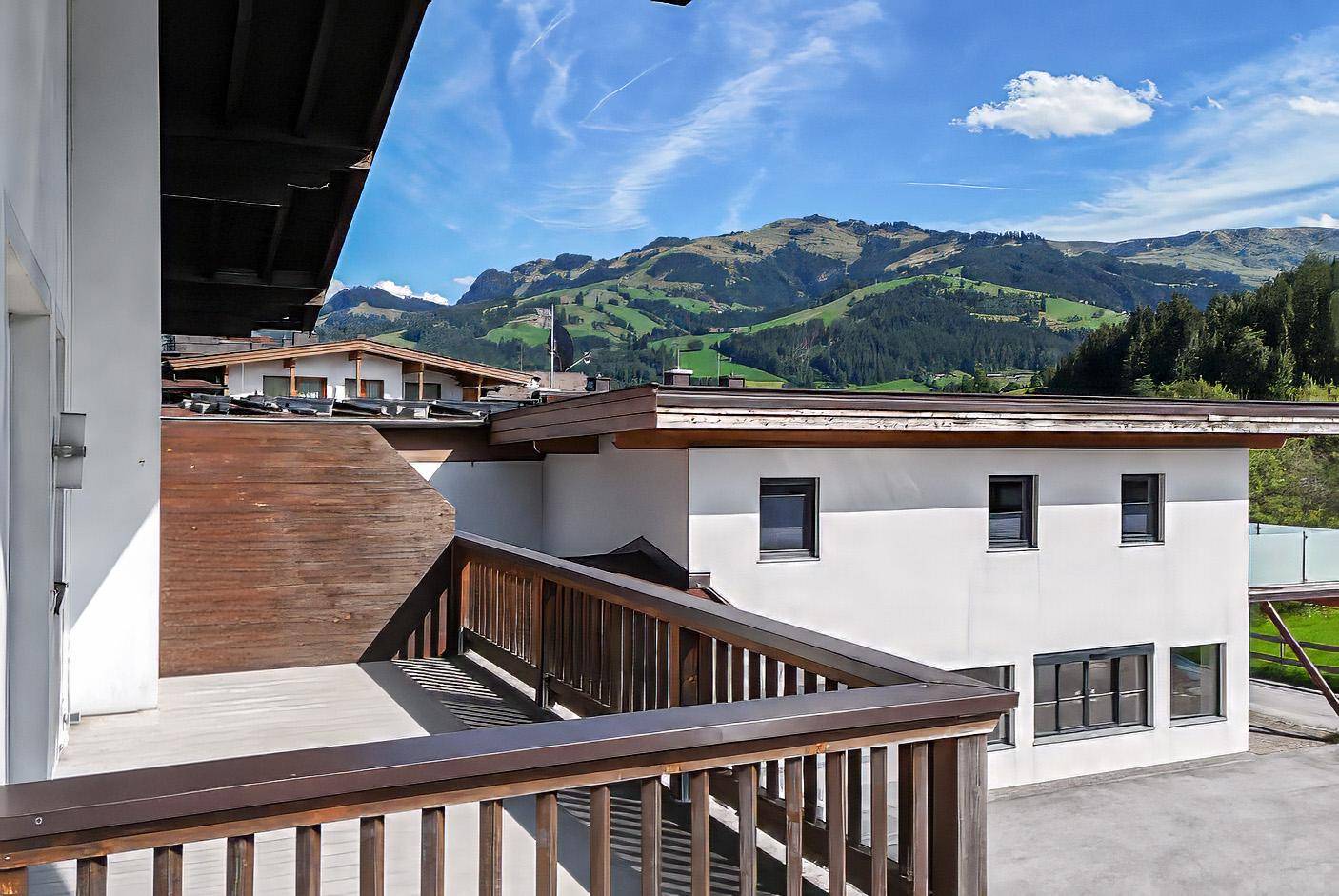 Geräumiger Balkon mit Holzgeländer und atemberaubendem Blick auf die grüne Berglandschaft.
