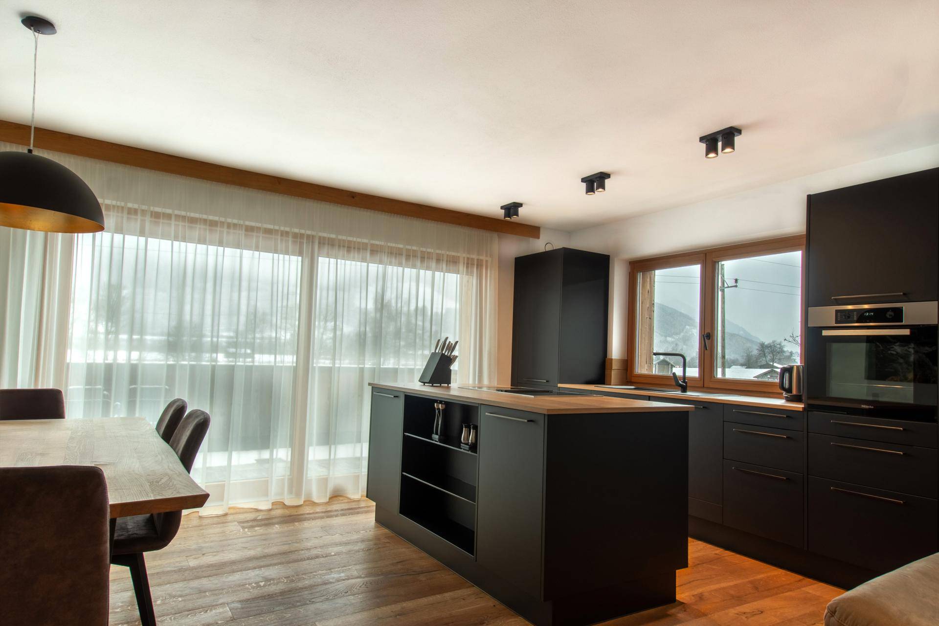 Offene Küche mit Kochinsel, Esstisch und Zugang zu einem großen Balkon.