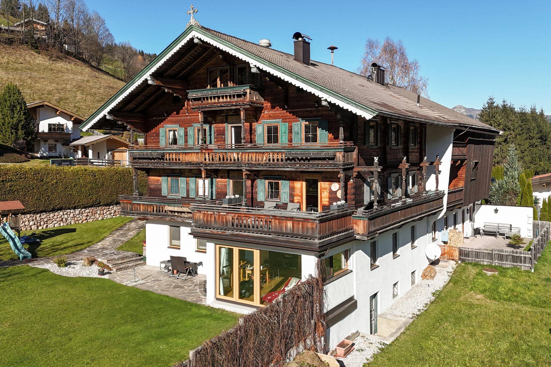 Charmantes Holzhaus im alpinen Stil mit mehreren Balkonen und einem gepflegten Gartenbereich.