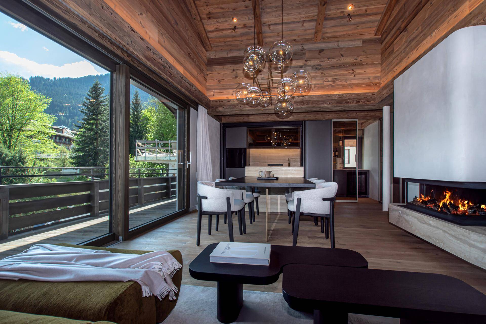 Geräumiger Wohn-Essbereich mit großen Fenstern, Bergblick und Zugang zum Balkon.