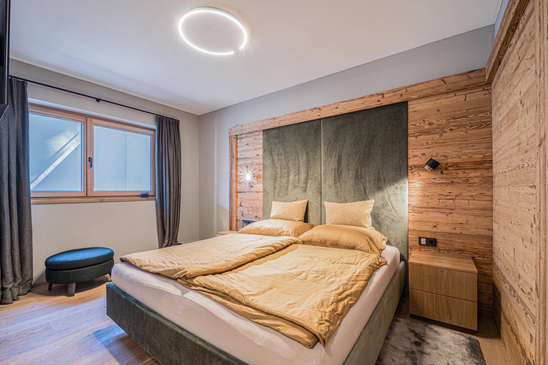 Komfortables Schlafzimmer mit Doppelbett, Holzwandverkleidung und modernem Design.