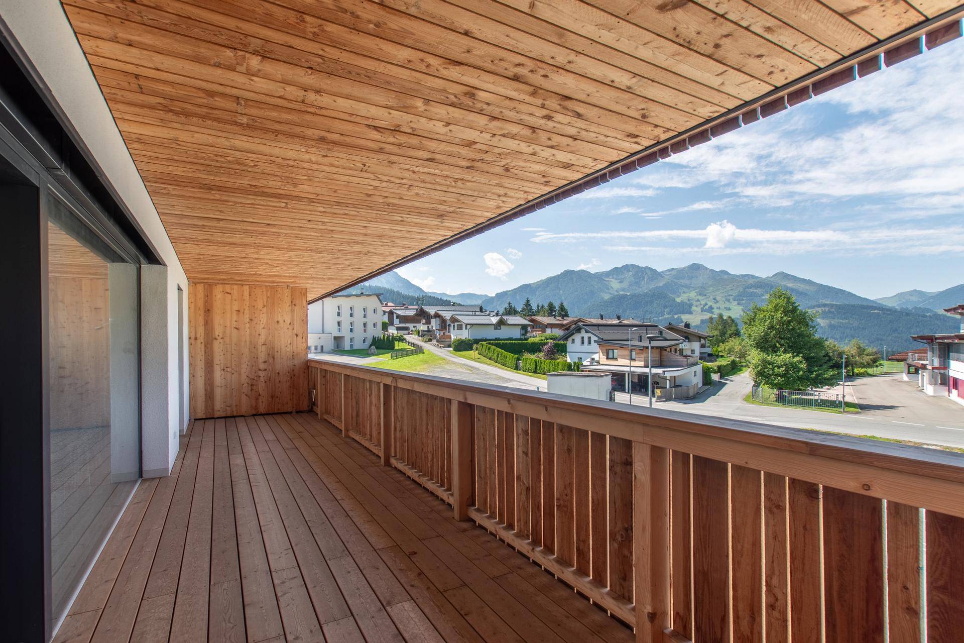 Geräumiger Holzbalkon mit Panoramablick auf die Berge und das umliegende Dorf.