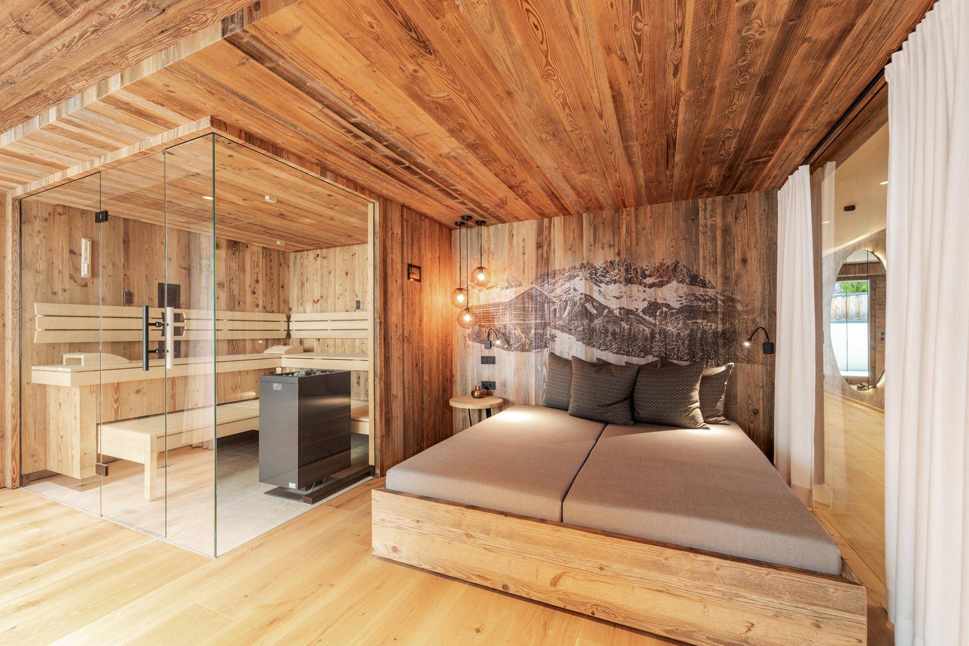 Schlafzimmer mit integrierter Sauna, Holzelementen und einem dekorativen Bergbild an der Wand.