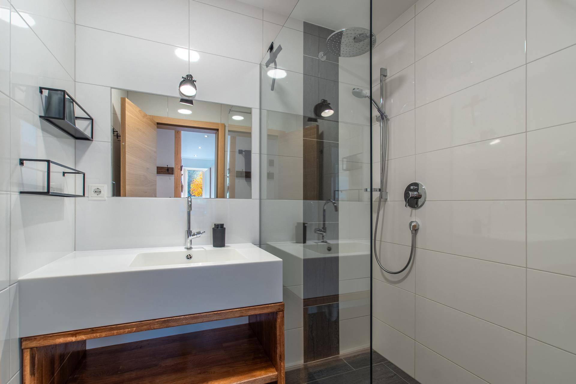 Modernes Badezimmer mit ebenerdiger Dusche, großem Spiegel und stilvollen Fliesen.
