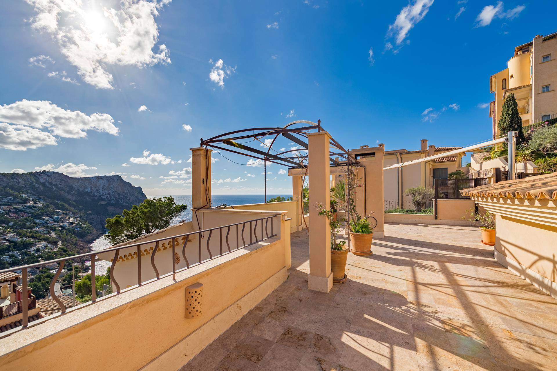 Große Sonnenterrasse mit Pergola, Blumentöpfen und atemberaubendem Blick auf das Meer und die Küste.