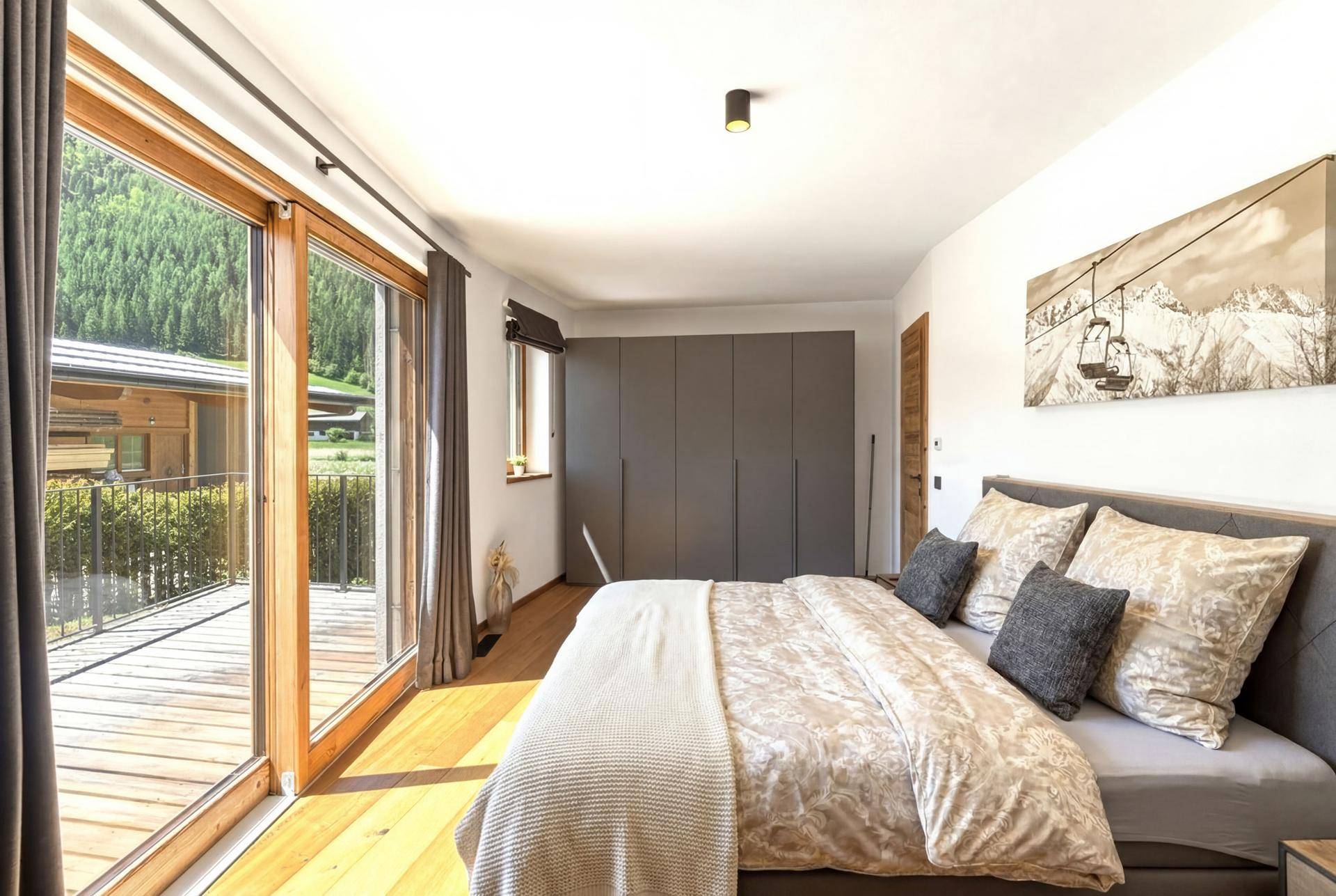 Schlafzimmer mit großem Bett, Einbauschränken und Zugang zu einem Balkon mit Bergblick.