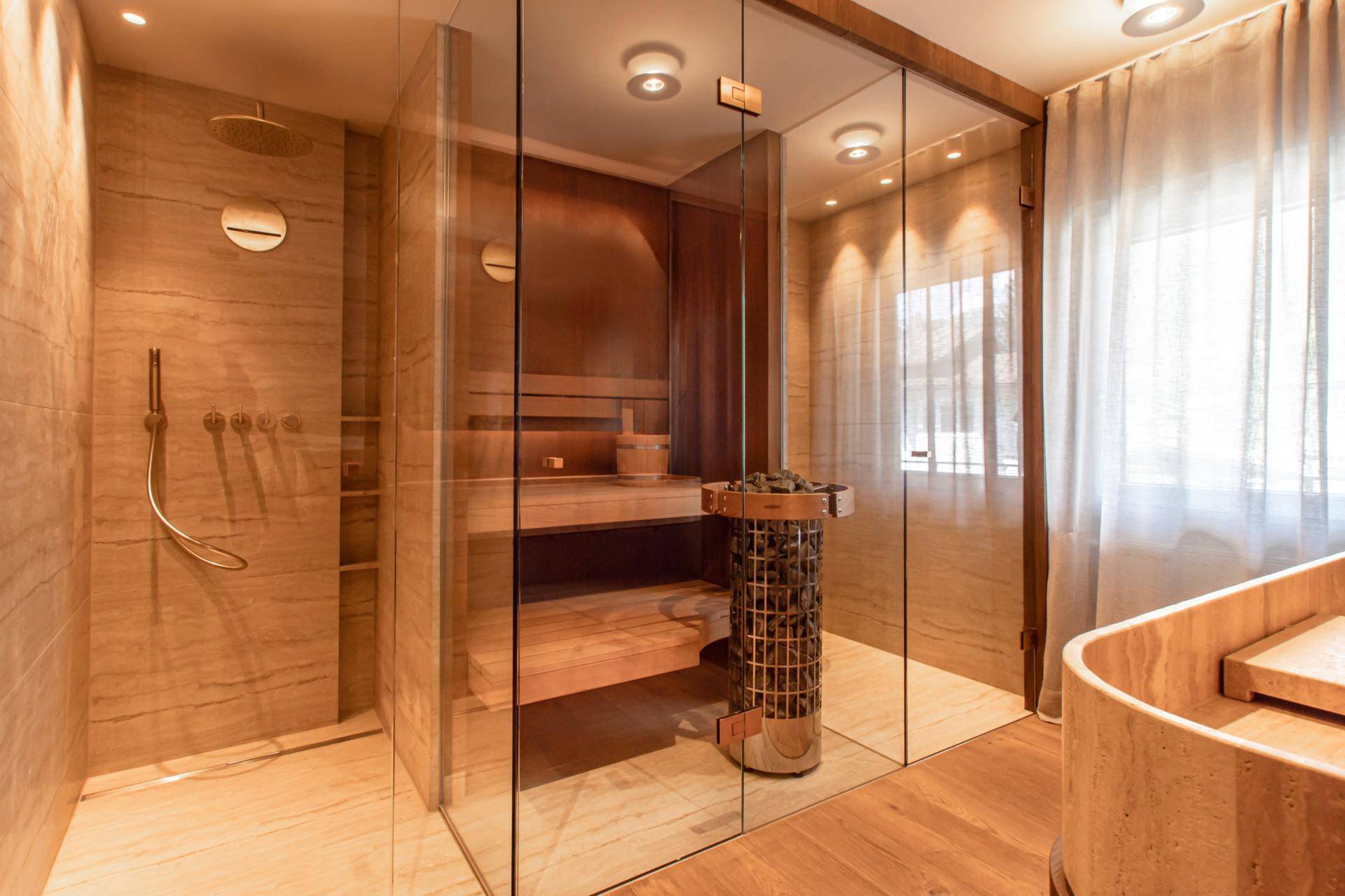 Luxuriöses Badezimmer mit begehbarer Dusche, integrierter Sauna und hochwertigen Steinfliesen.