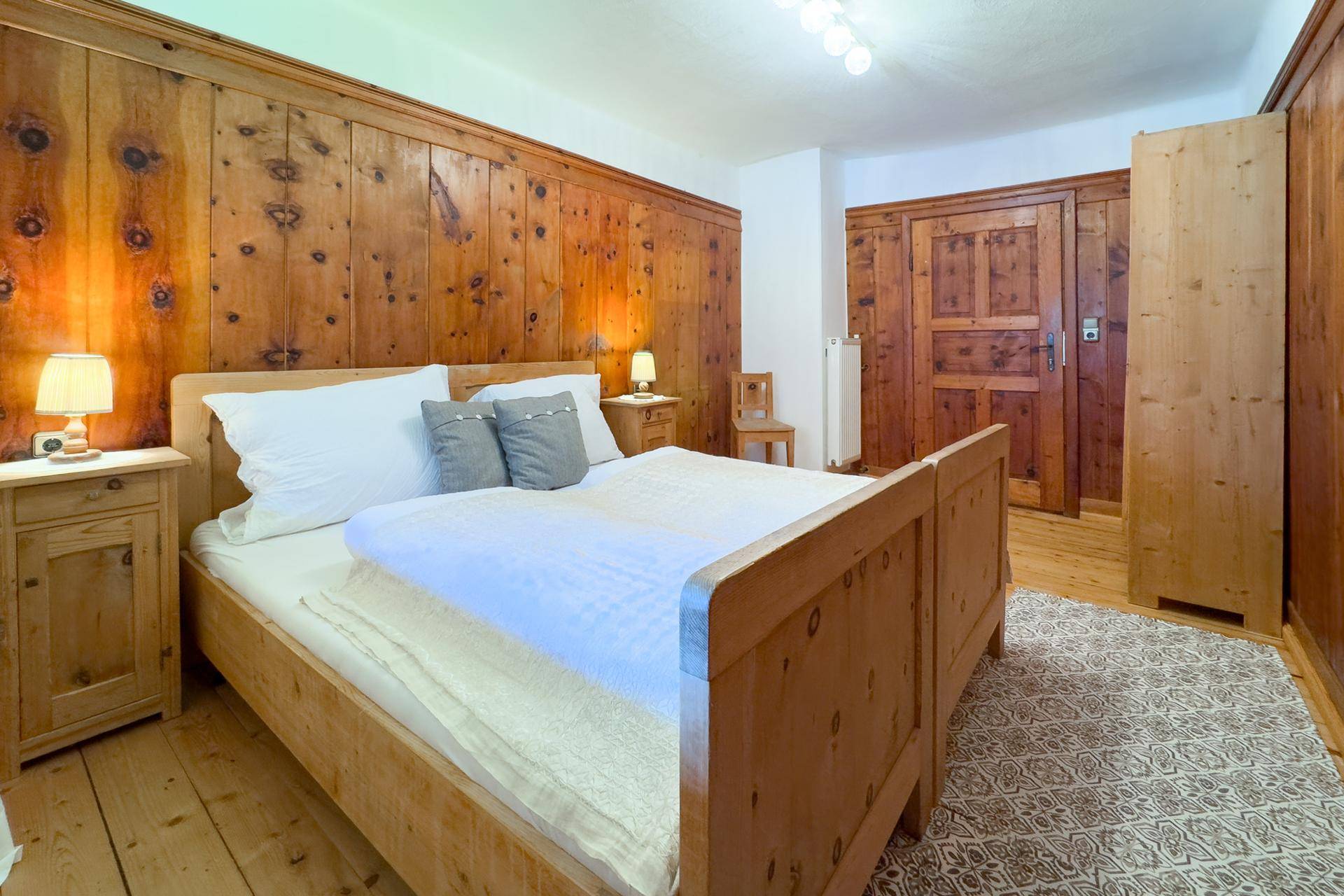 Gemütliches Schlafzimmer mit Holzbett, Holztäfelung und traditionellen Nachttischen.