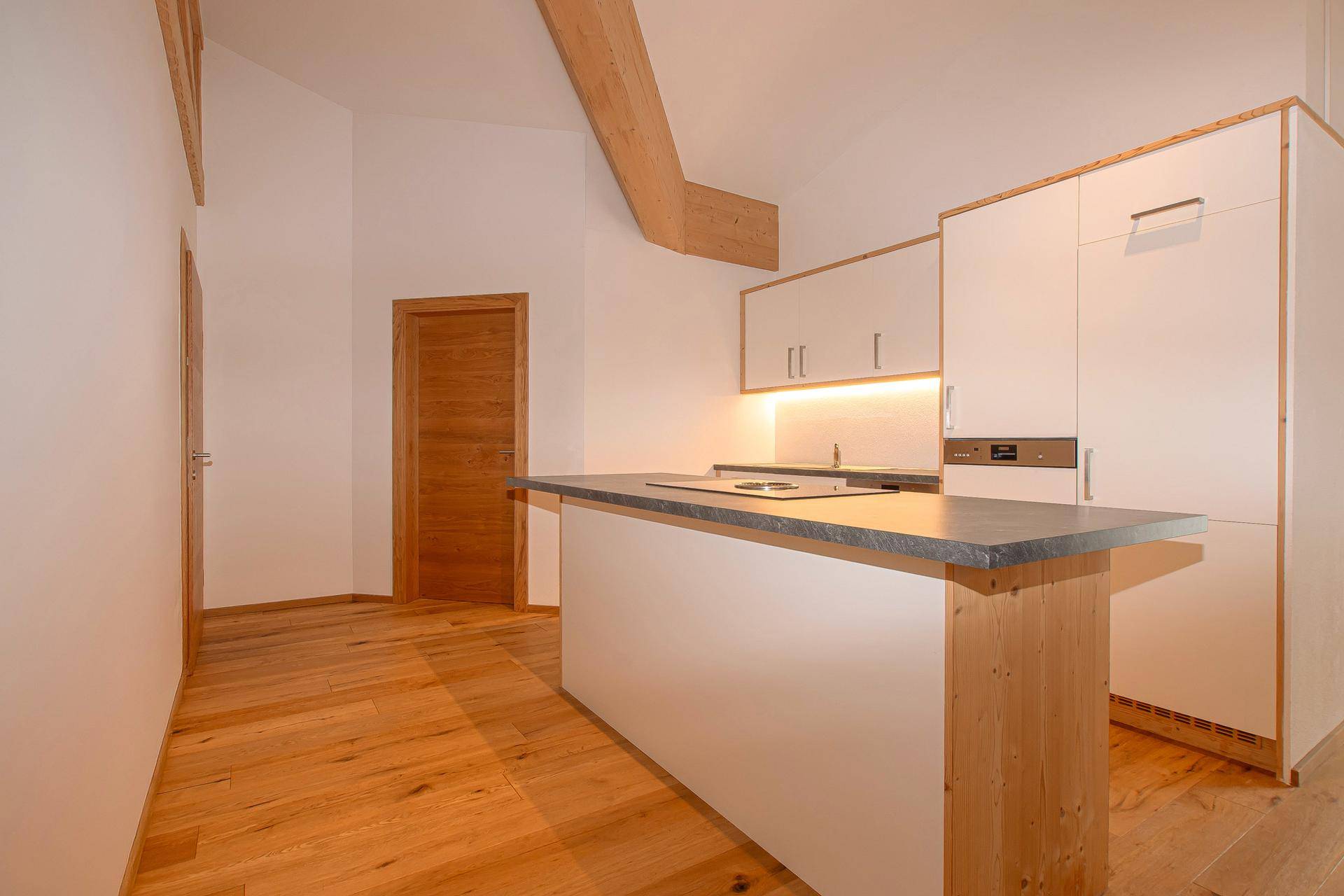 Moderne Einbauküche mit Kücheninsel, integrierten Geräten und hellem Holzfußboden.