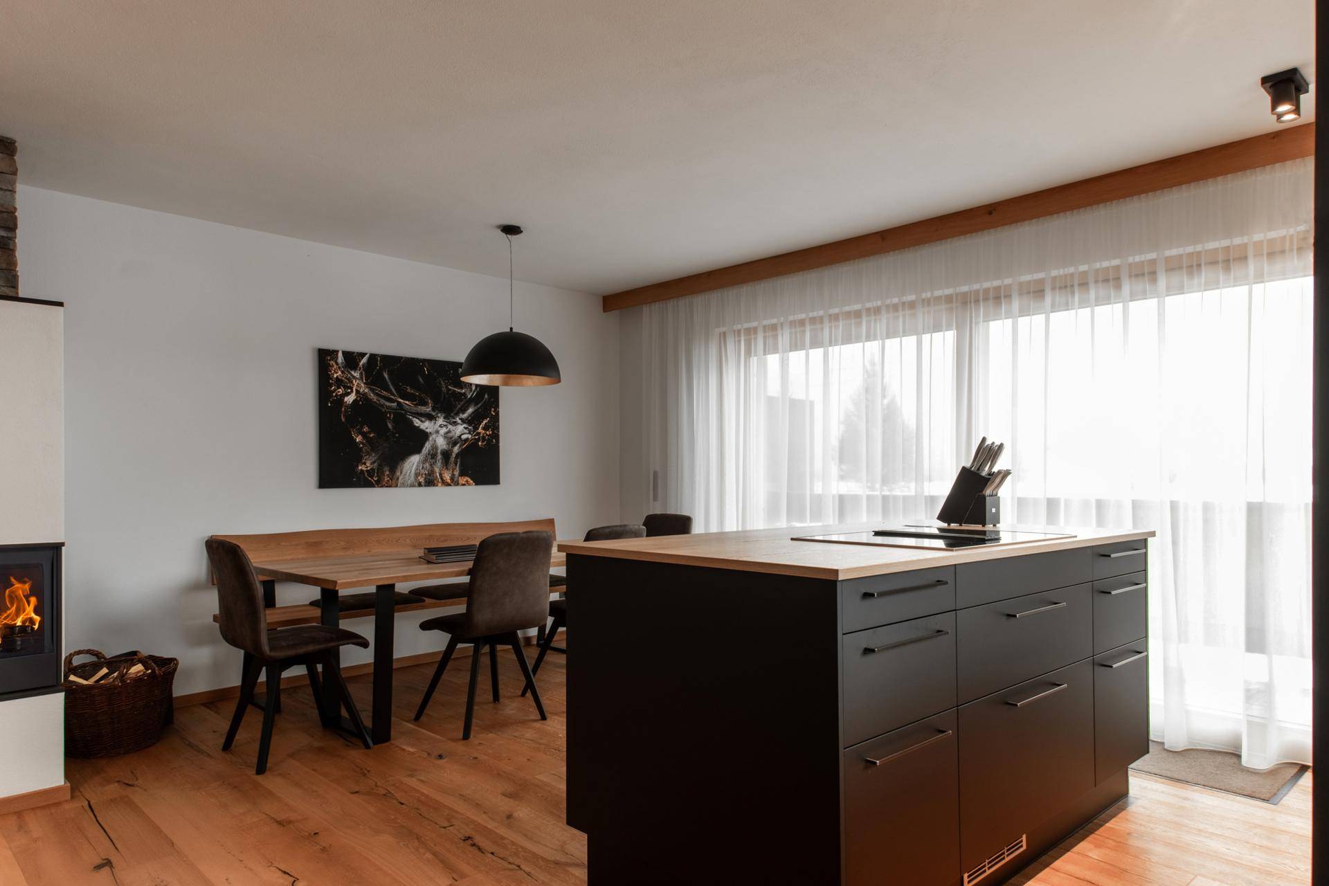 Gemütlicher Essbereich mit Holztisch, Kamin und großen Fenstern zum Balkon.