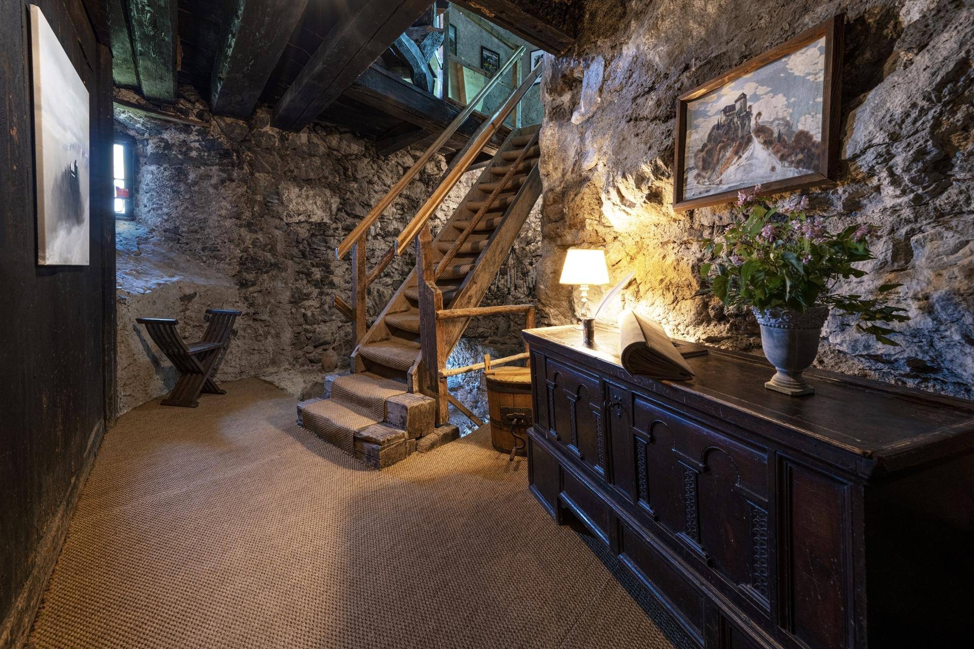 Rustikaler Eingangsbereich mit Steinfassade, Holztreppe und antiken Möbeln.