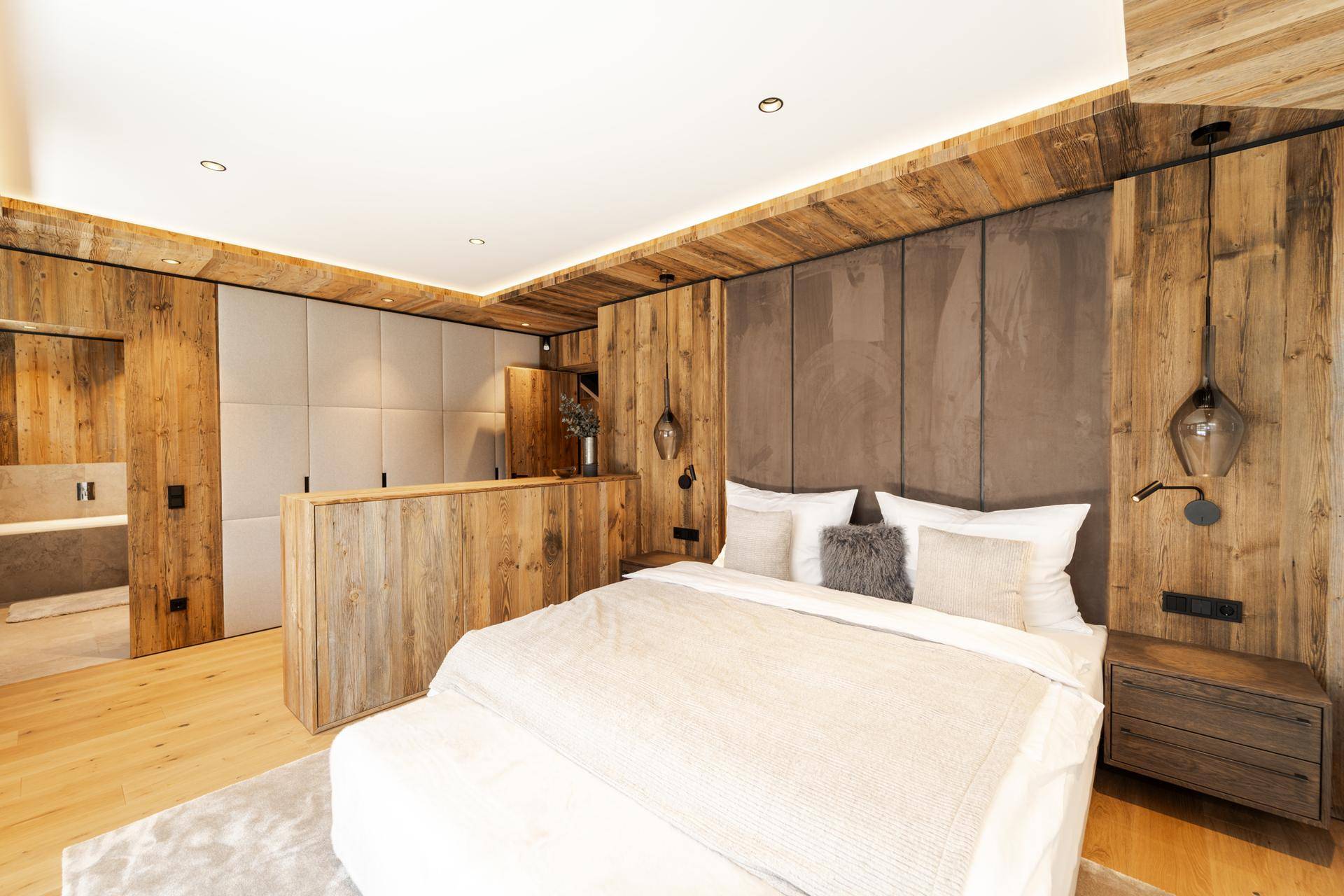 Stilvolles Schlafzimmer mit Holzwänden, großem Bett und integrierten Schränken für viel Stauraum.