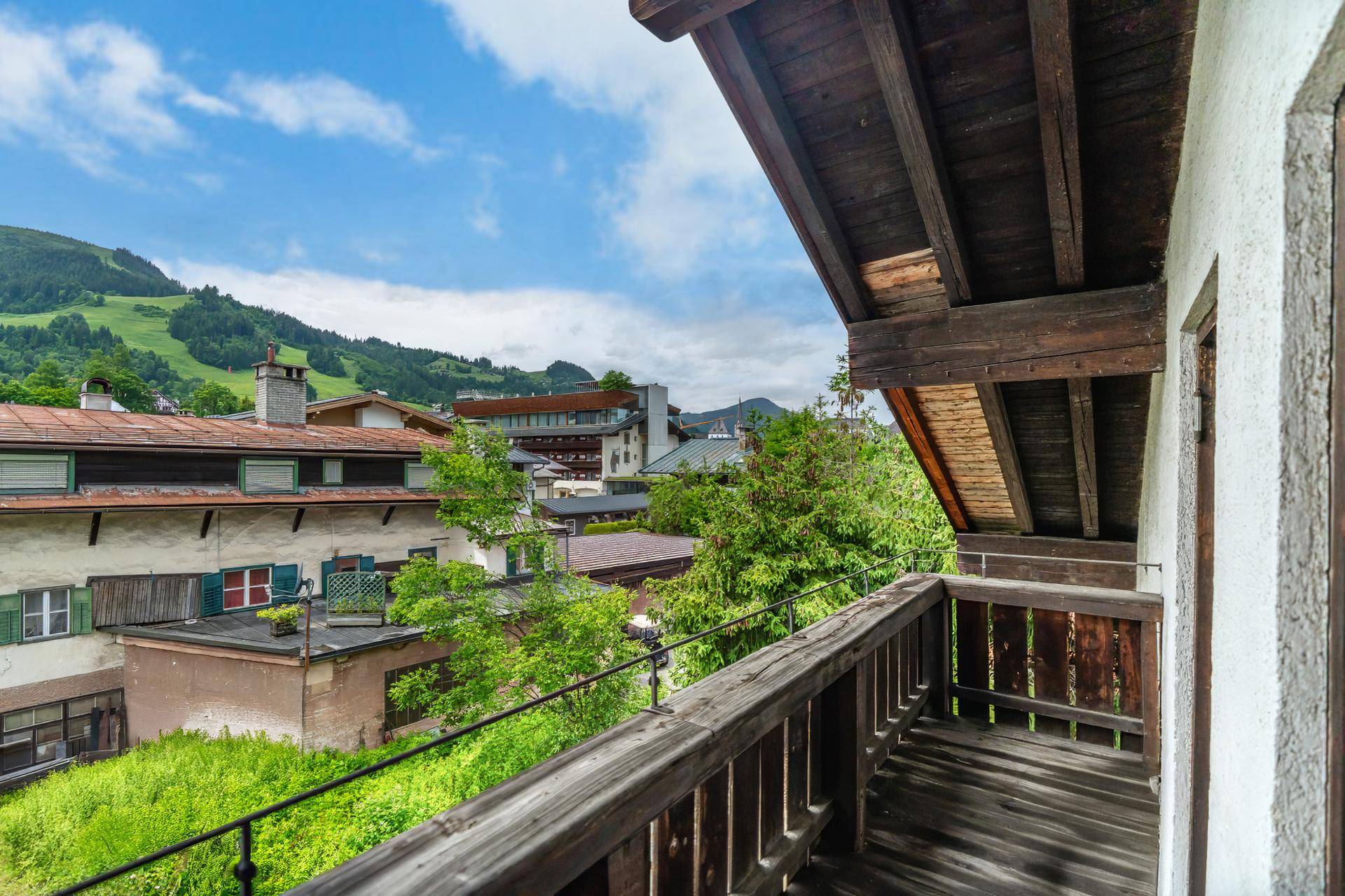 Traditioneller Holzbalkon mit Blick auf die umliegenden Häuser und grüne Hügel.