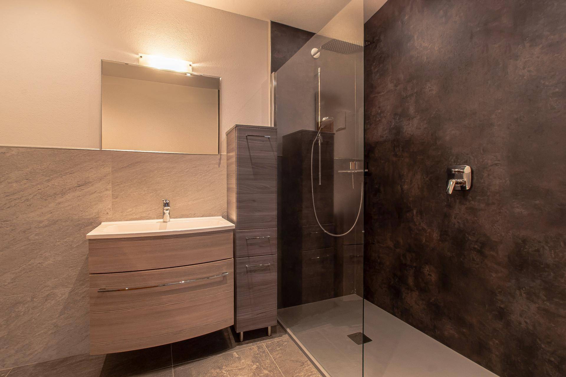 Modernes Badezimmer mit ebenerdiger Dusche, stilvollen Fliesen und elegantem Waschtisch.