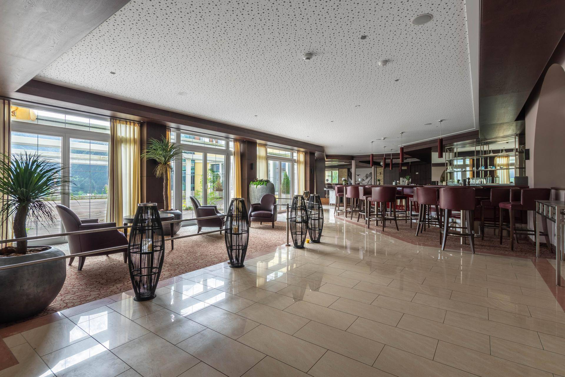 Elegante Hotelbar mit großen Fenstern, bequemen Sitzgelegenheiten und einem glänzenden Fliesenboden.