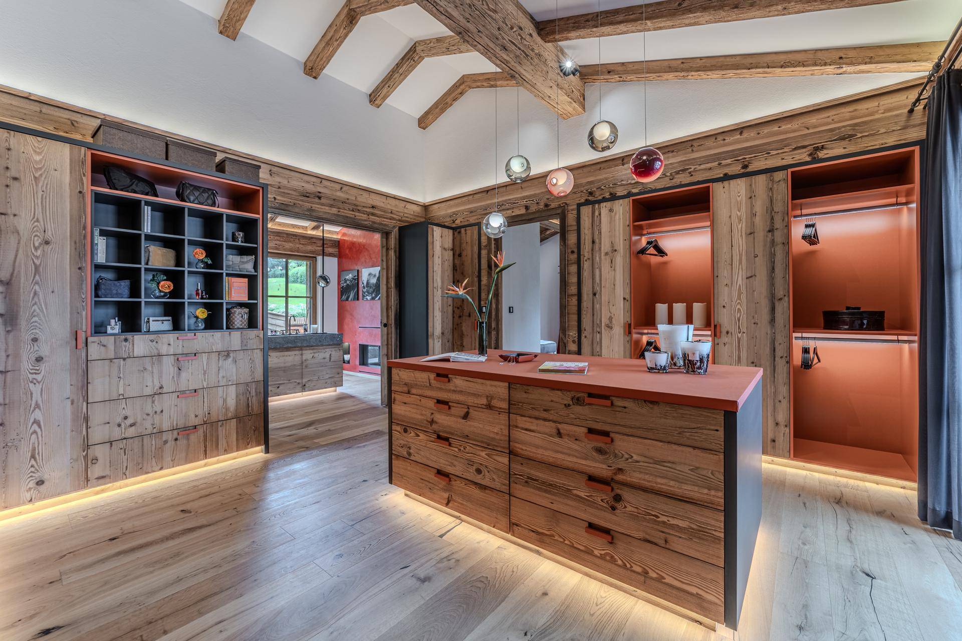 Geräumiger begehbarer Kleiderschrank mit Holzeinbauten, Mittelinsel und indirekter Beleuchtung.