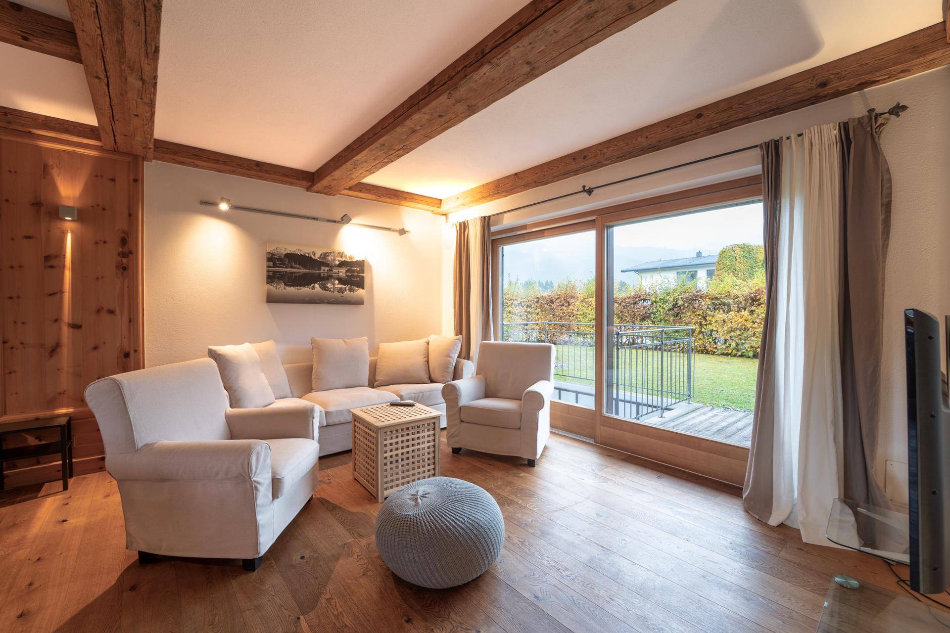 Helles Wohnzimmer mit bequemen Sofas, Holzbalken und Blick in den Garten.