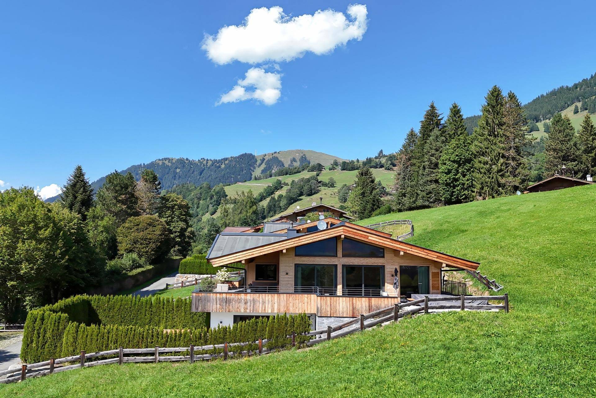 Charmantes Chalet mit großen Fenstern und Holzelementen, eingebettet in eine malerische Berglandschaft.